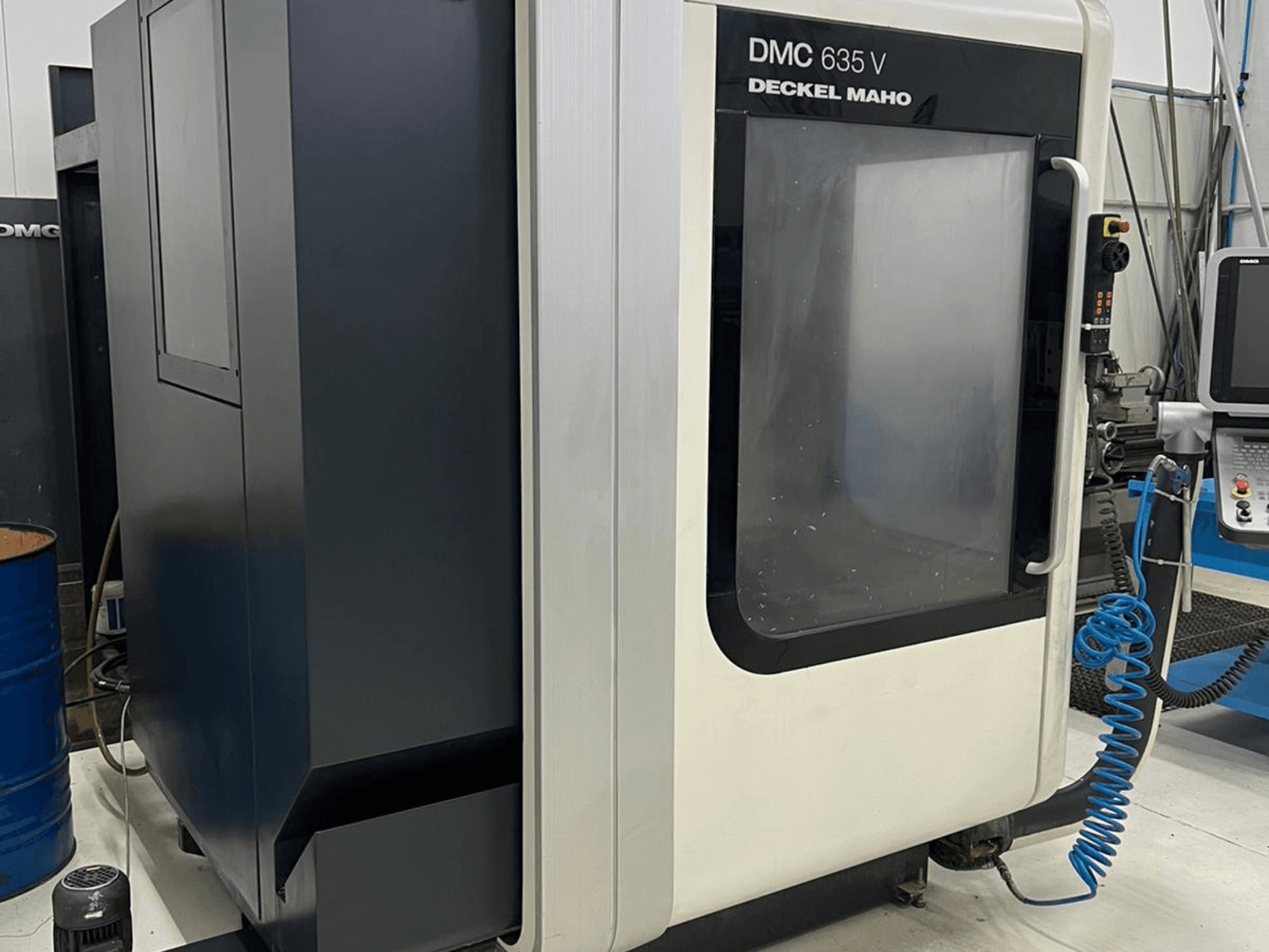 Фрезерний верстат DMC 635 V від Deckel Maho, вид збоку з панеллю керування та частково відкритими дверцятами.
