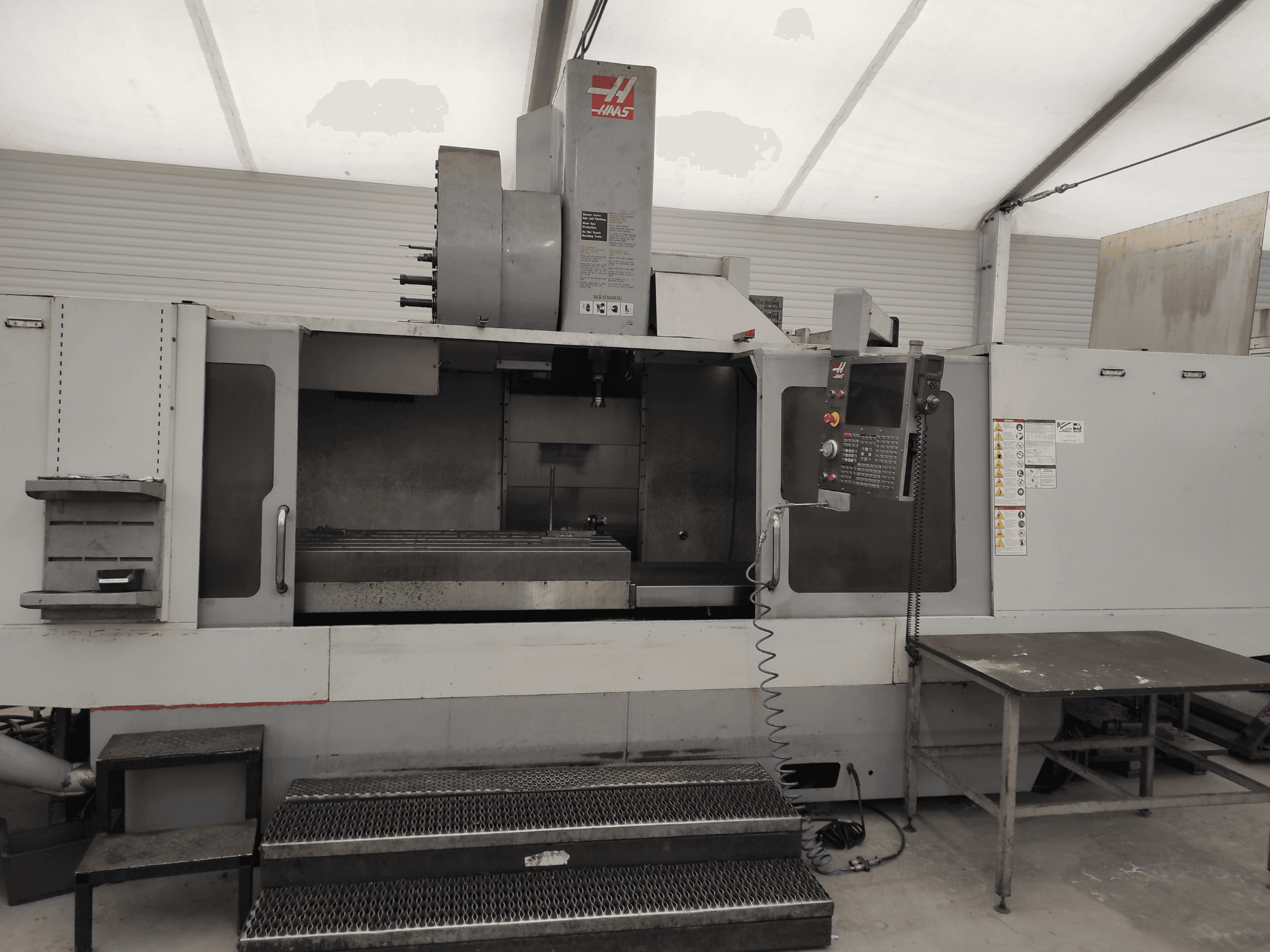 Вертикальний обробний центр HAAS VF-10/50HE, вид спереду: панель керування, станина верстата та доступна сходинка для роботи.