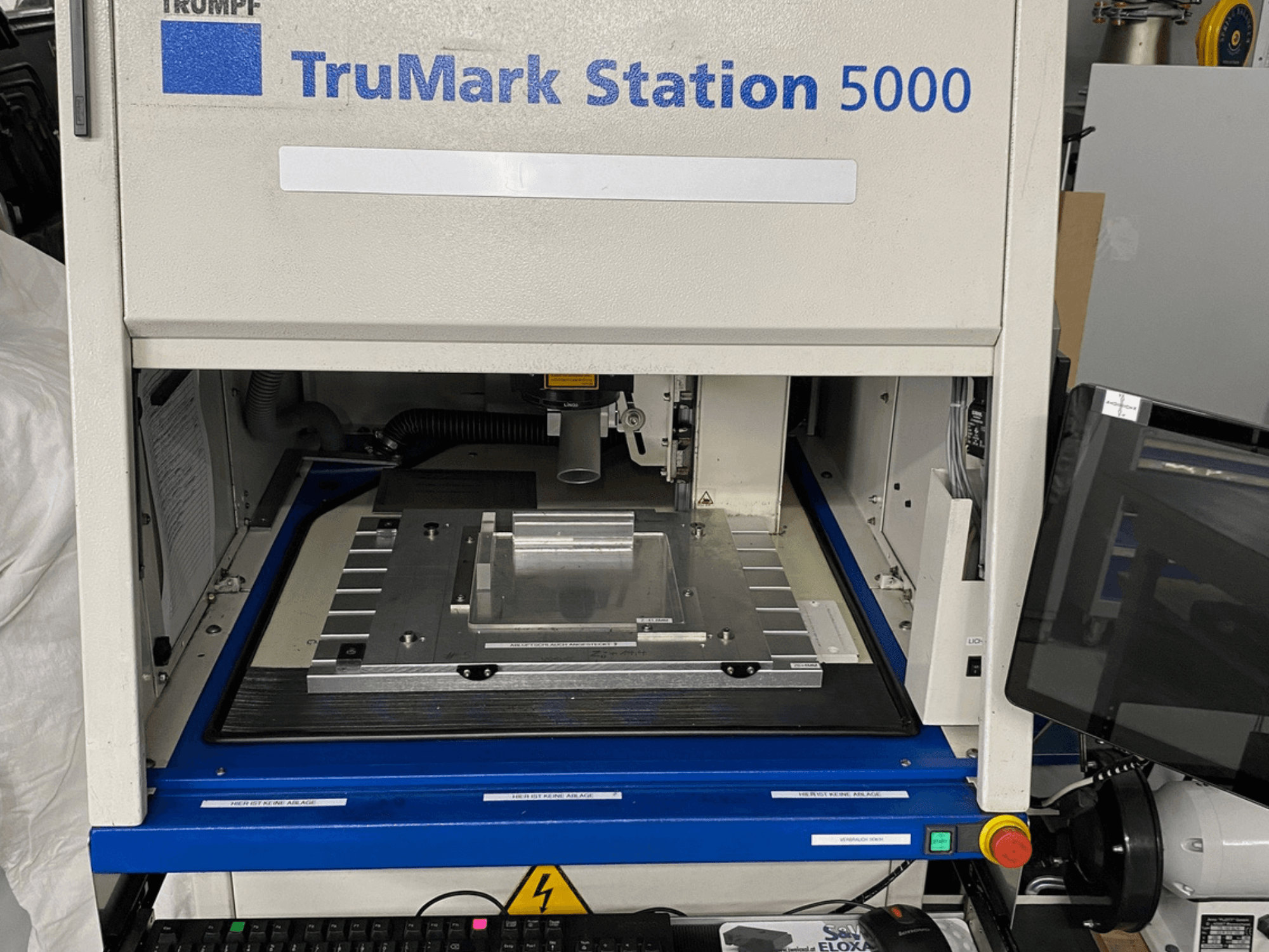 Лазерний маркувальник TruMark Station 5000 спереду: робочий стіл, елементи керування та екран моніторингу.