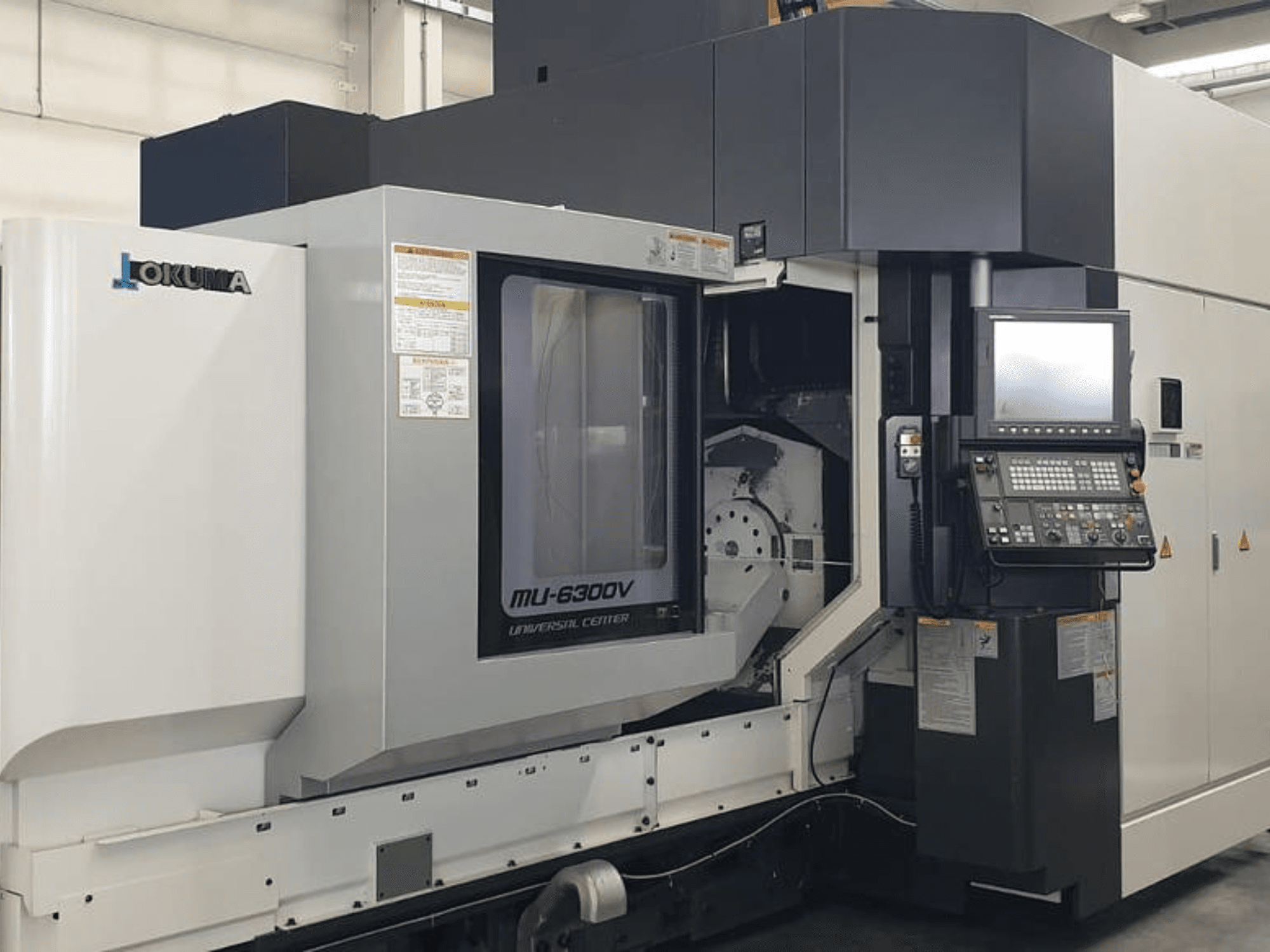 Вертикальний обробний центр Okuma MU 6300 V, вид спереду з панеллю керування та деталями зони обробки.