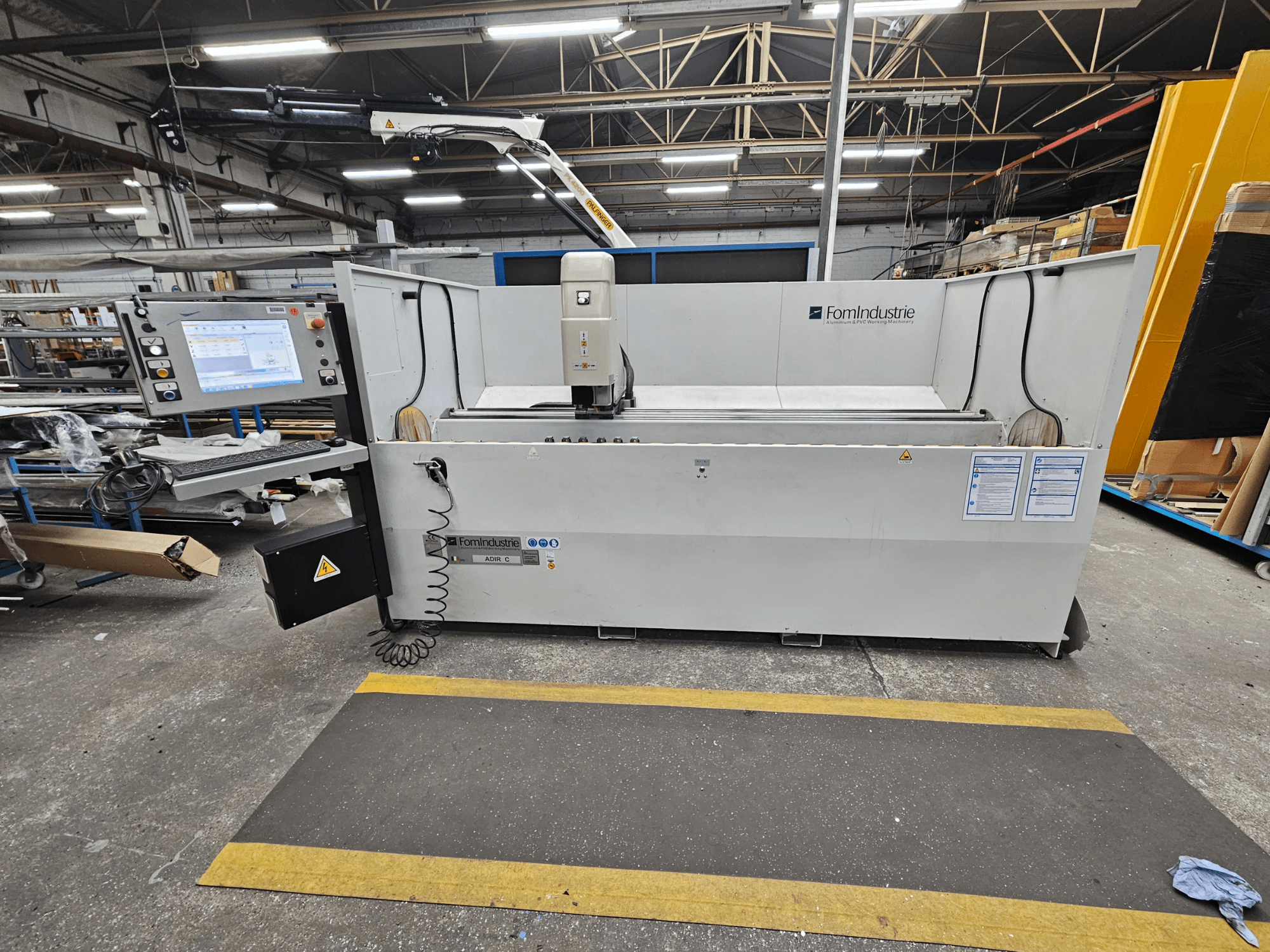 Вертикальний обробний центр FomIndustrie ADIR C в майстерні, вид спереду з панеллю керування та деталями верстата.