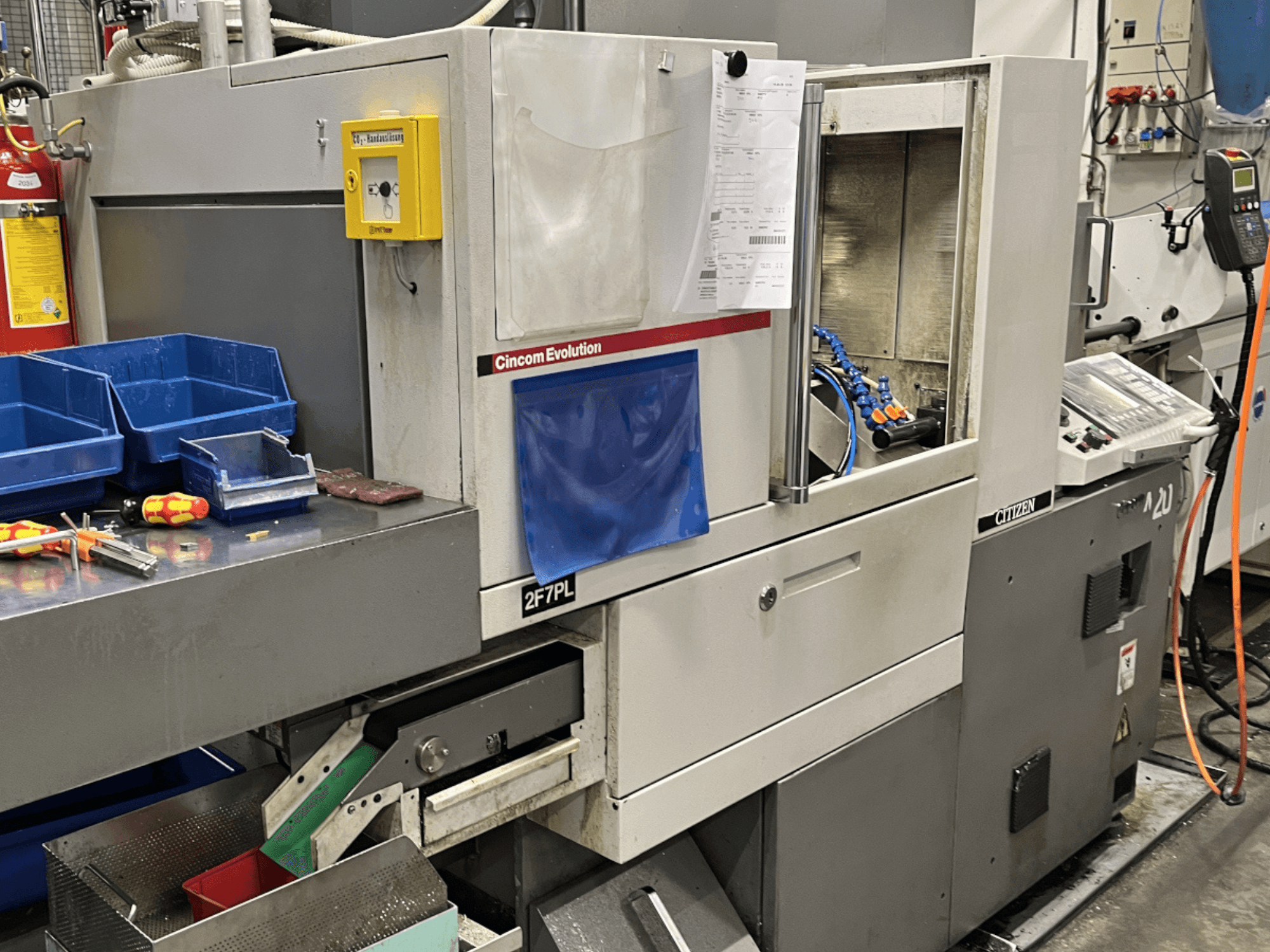 Обробний центр Cincom Evolution 2F7PL, вигляд спереду; елементи керування, бункери для інструментів та детальна панель керування.