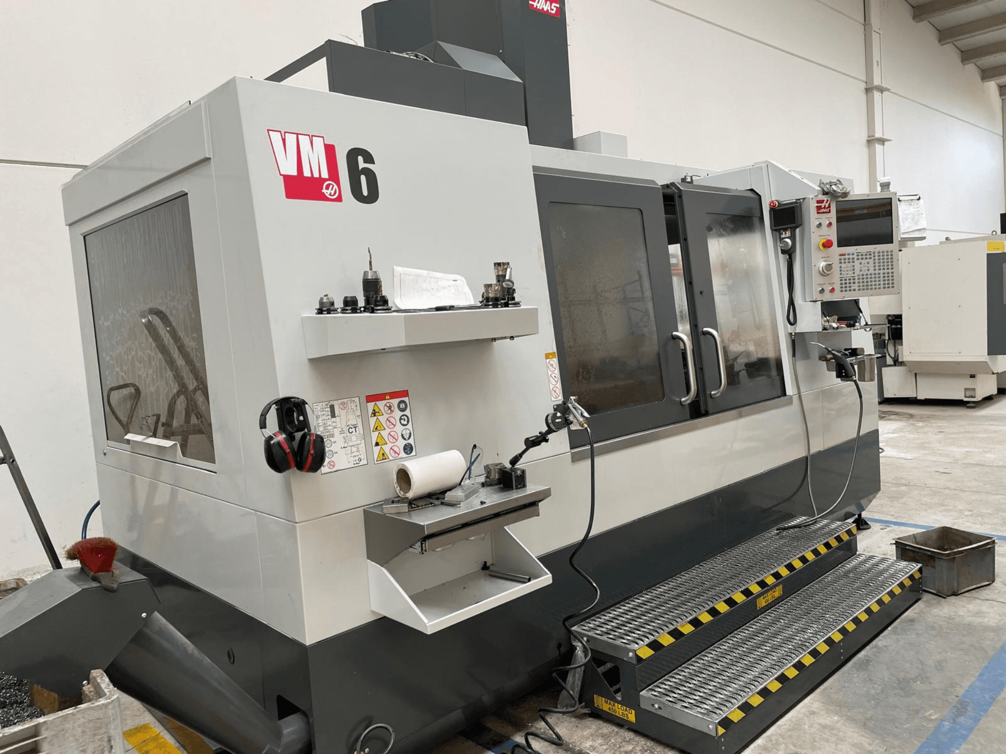 Вертикальний обробний центр Haas VM-6, вид спереду з панеллю керування, тримачами інструментів та засобами безпеки.