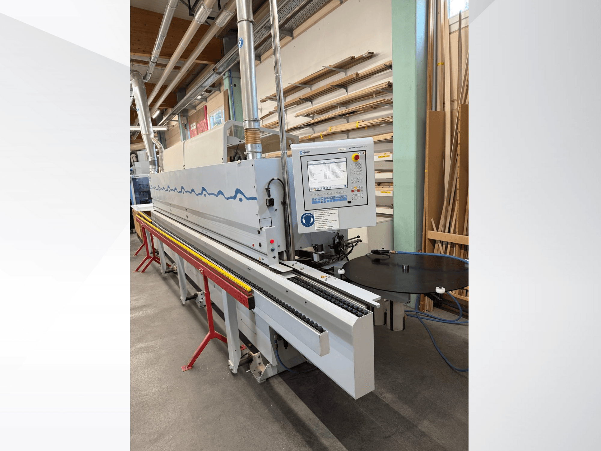 Вид спереду автоматичного кромкооблицювального верстата HolzHer з панеллю керування, конвеєрною системою та круглим опорним столом.