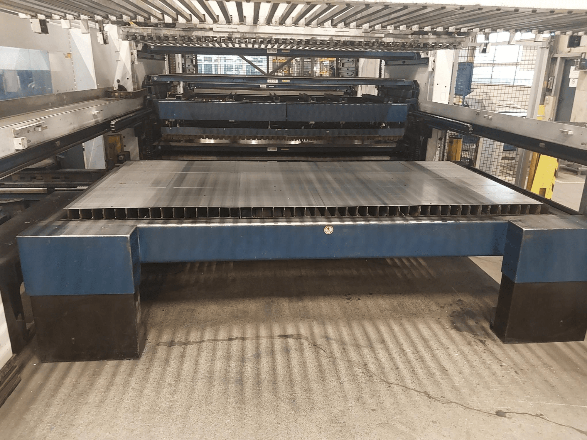 Вид спереду машини для лазерного різання TRUMPF TruLaser 3030 L20 CO2 з великим столом для різання та опорною конструкцією.