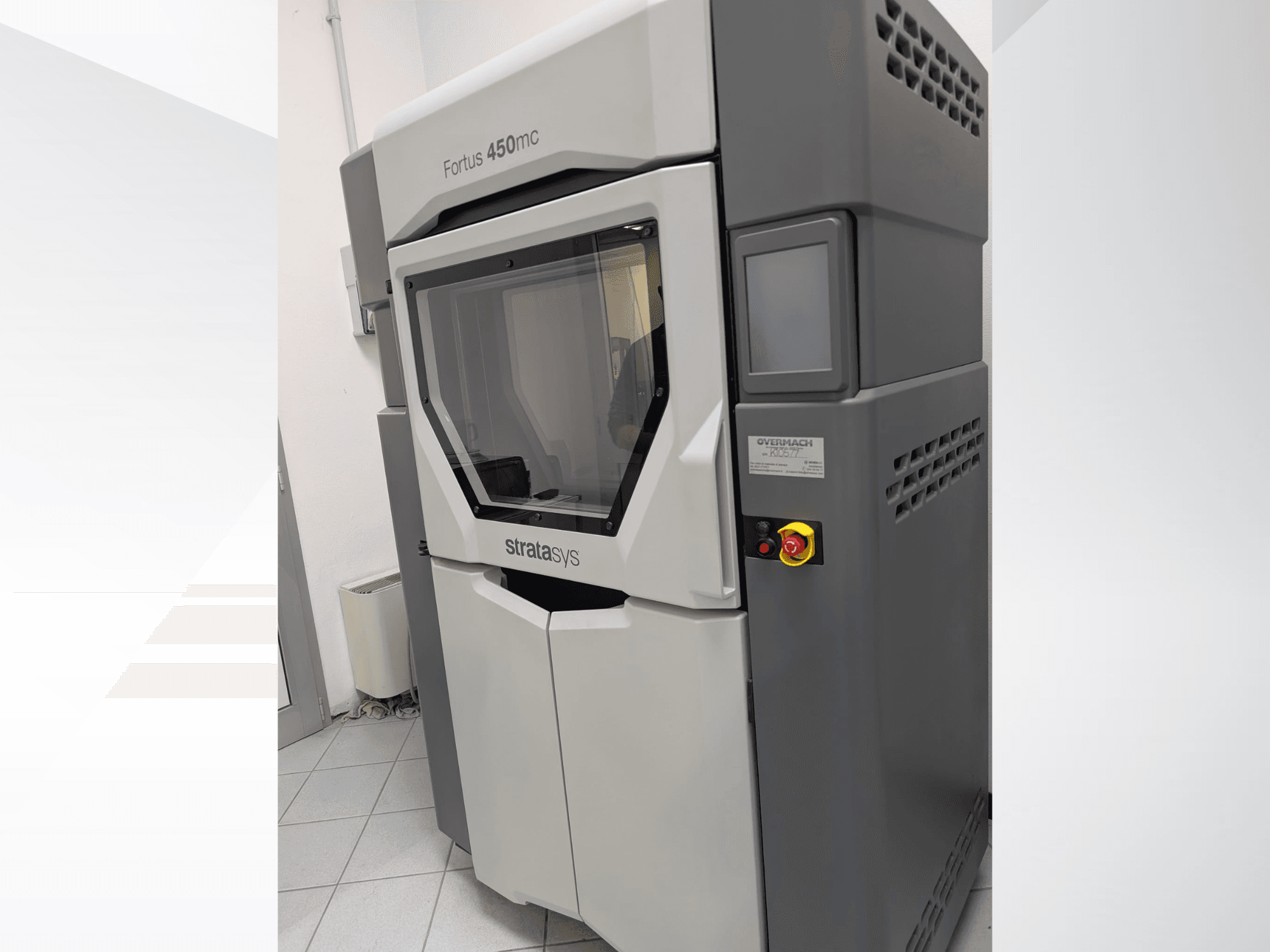 Пластиковий 3D-принтер Fortus 450mc показаний збоку, з прозорою передньою панеллю і кнопками керування збоку.