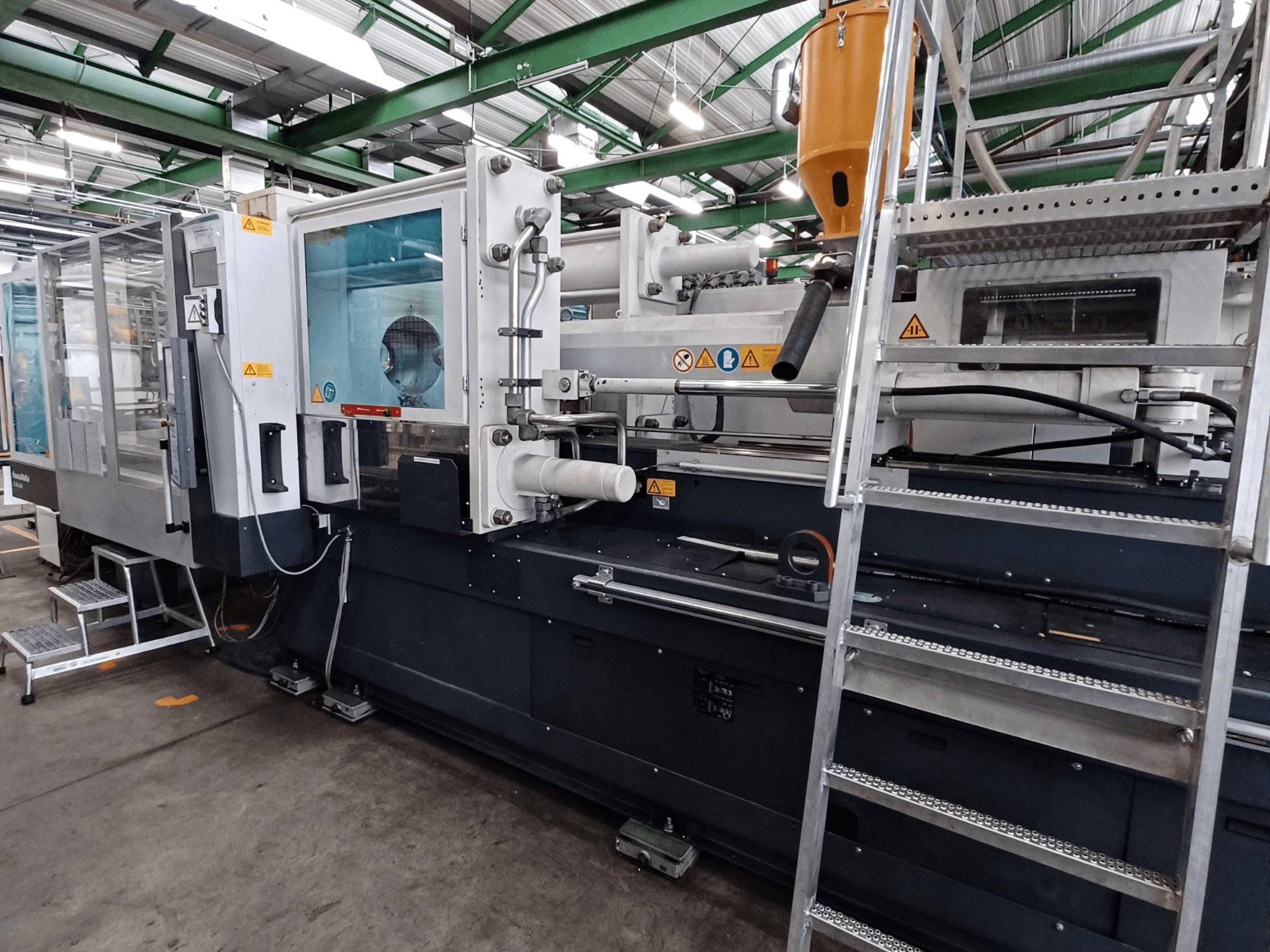 Промислова машина для лиття під тиском з чітким видом спереду, що показує маркування бренду, панель управління і бункер для матеріалу.