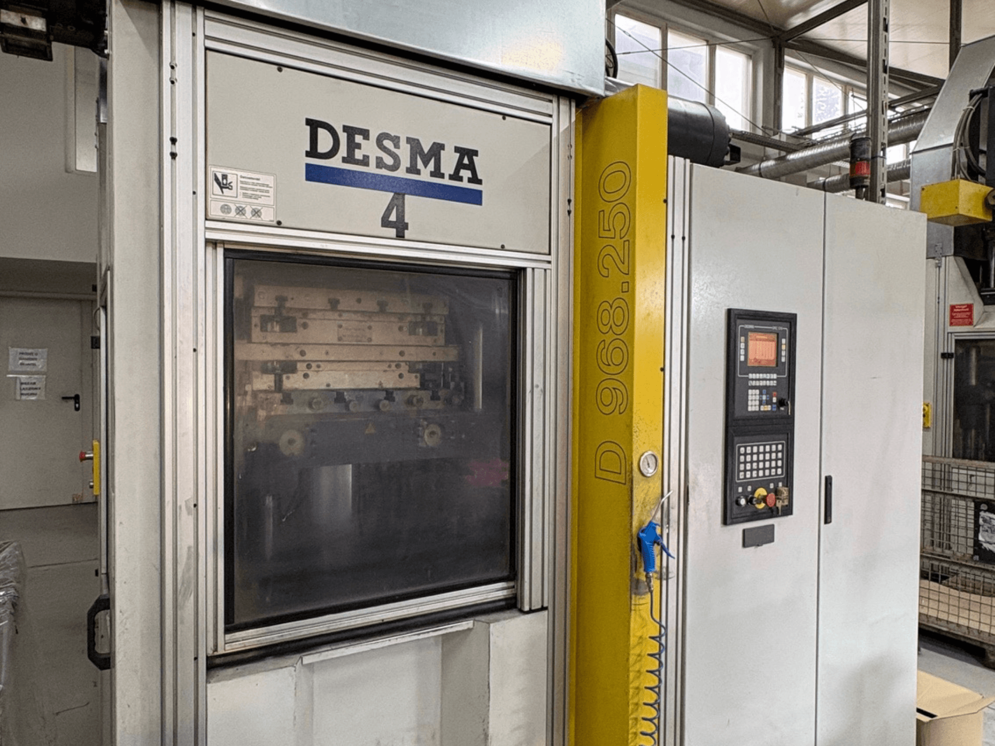 Вертикальна машина для лиття під тиском Kloeckner Desma 968.250, вид спереду з панеллю керування та деталями машини.