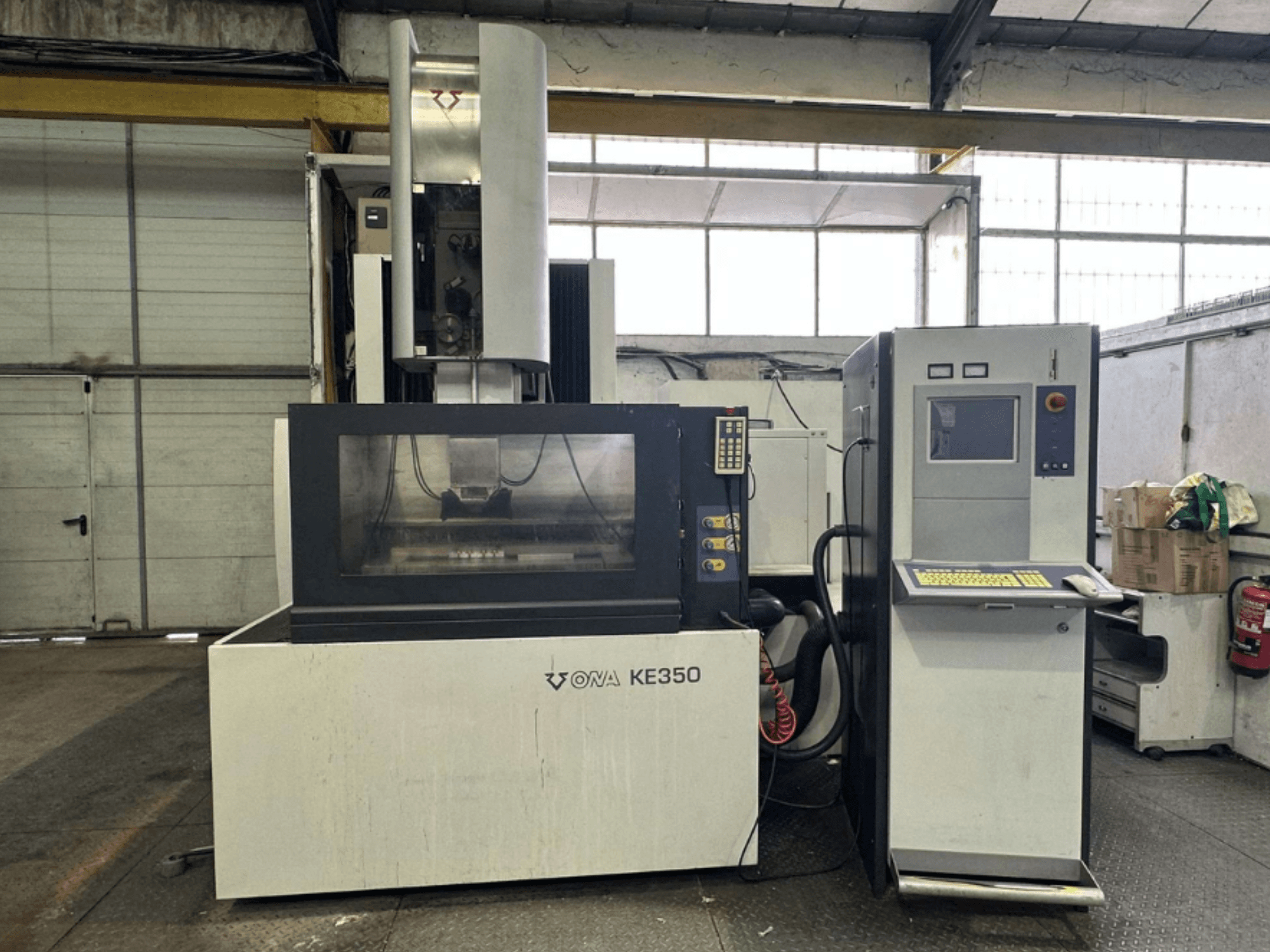 Вид спереду верстата з ЧПК ONA KE350 з панеллю керування, екраном дисплея і різними кнопками, розташований в промислових умовах.