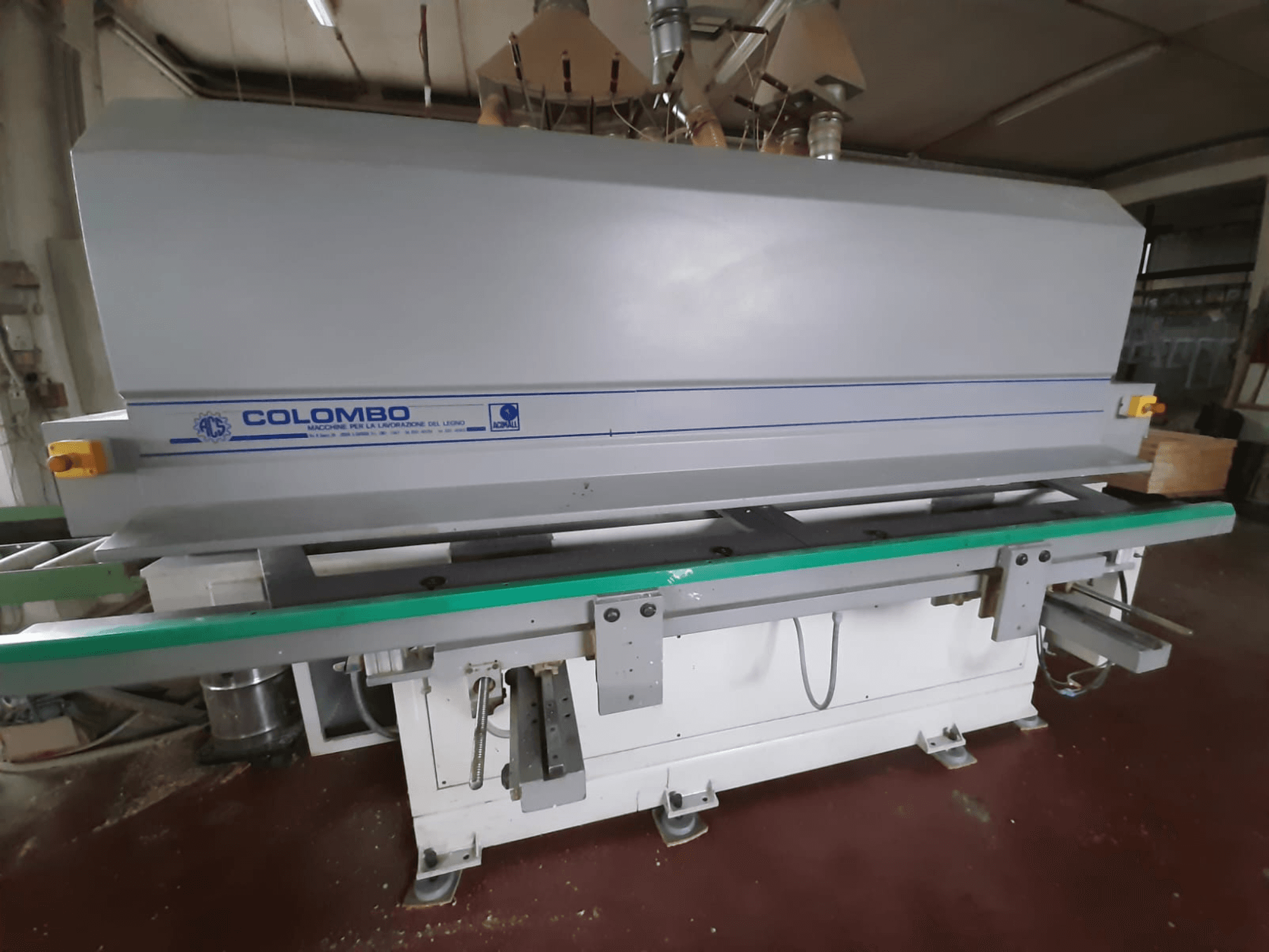 Деревообробний верстат Colombo, вид спереду, з довгим зеленим столом, кнопками керування та сірим корпусом з синіми акцентами.