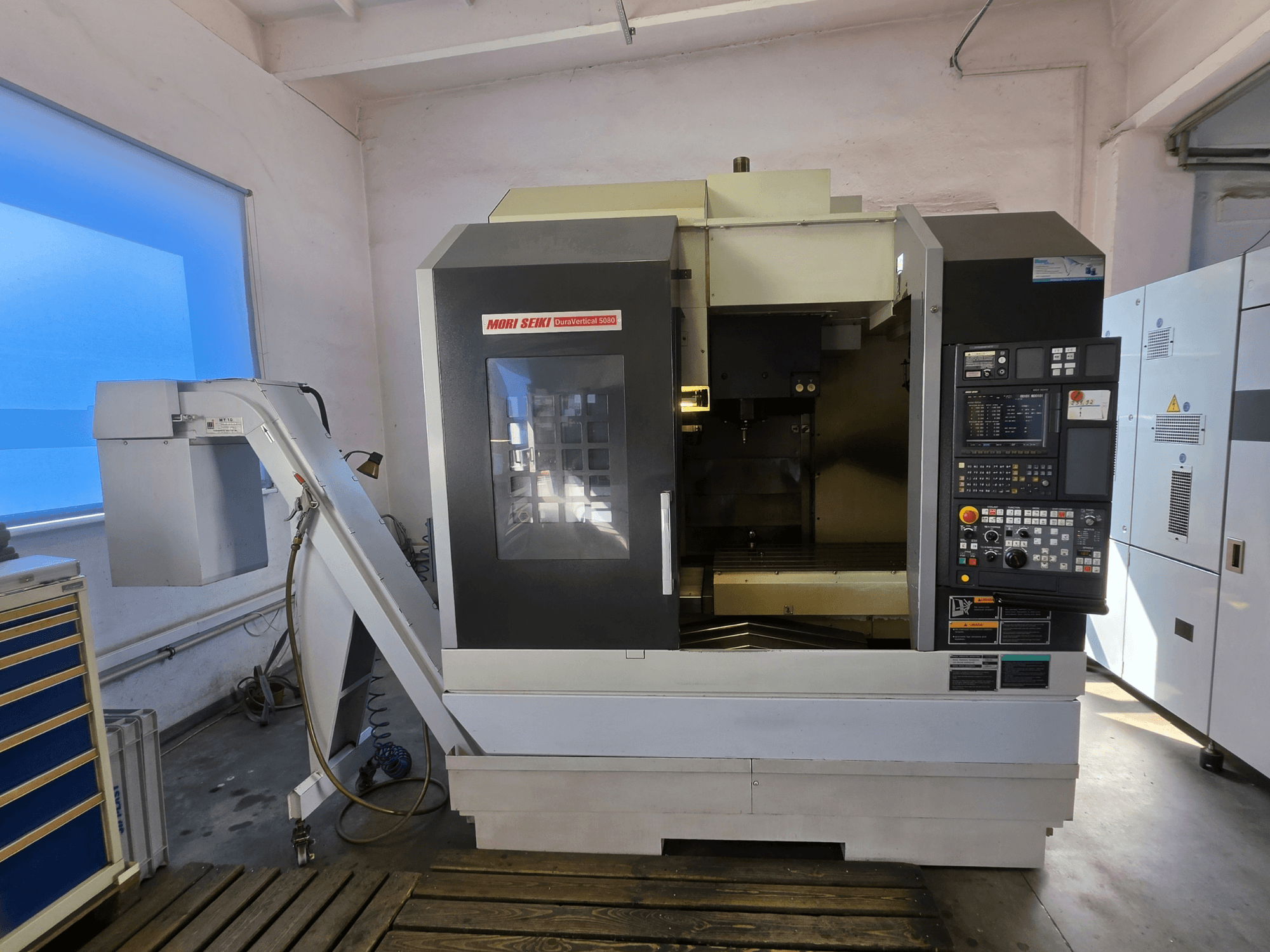 Вертикальний обробний центр MORI SEIKI DuraVertical 5080, вид спереду, на якому видно панель управління, шпиндель та тримач інструменту.