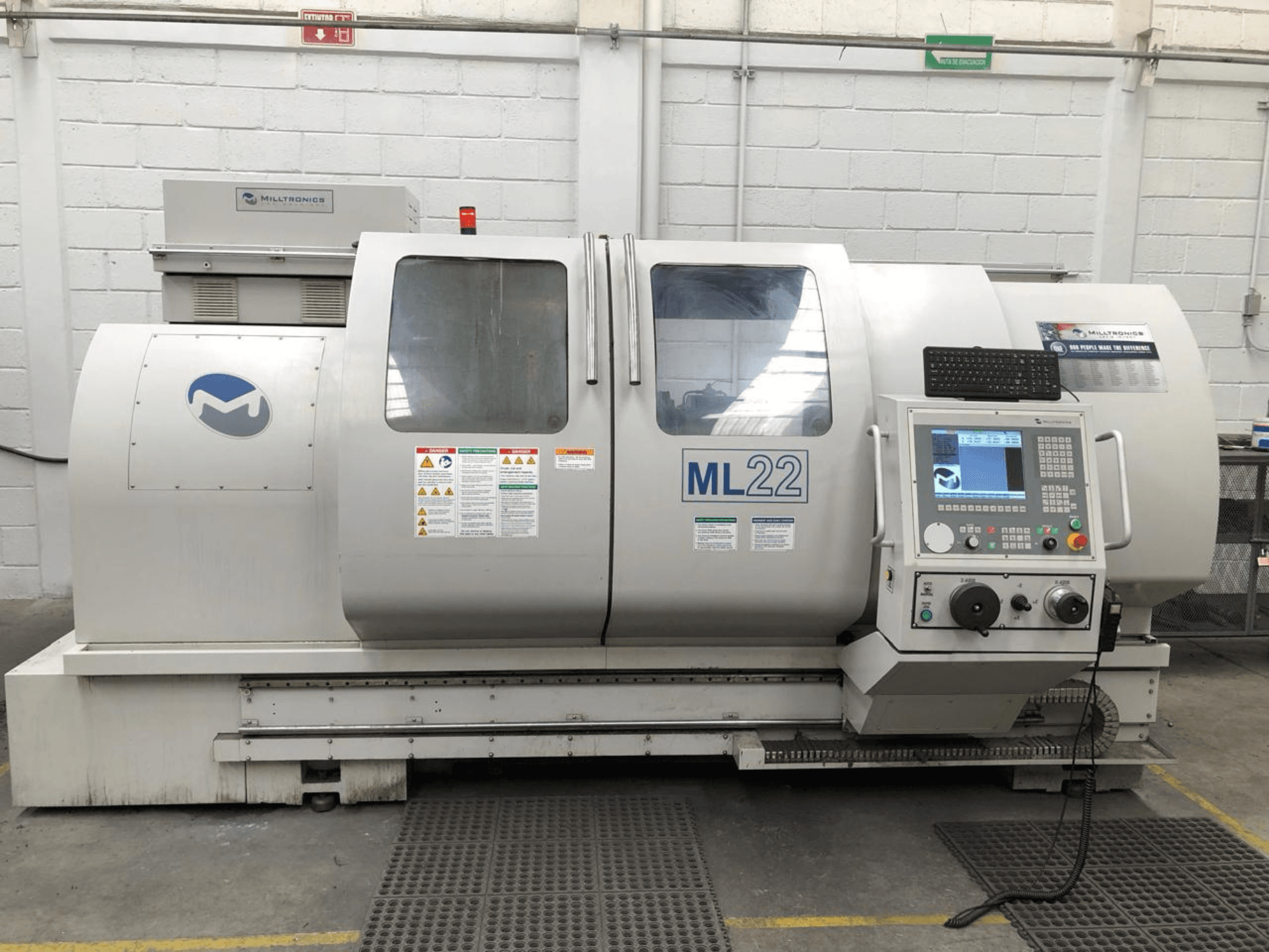 Вертикальний обробний центр MILLTRONICS RH 20, вид спереду з панеллю керування, логотипом бренду та етикетками безпеки на верстаті.