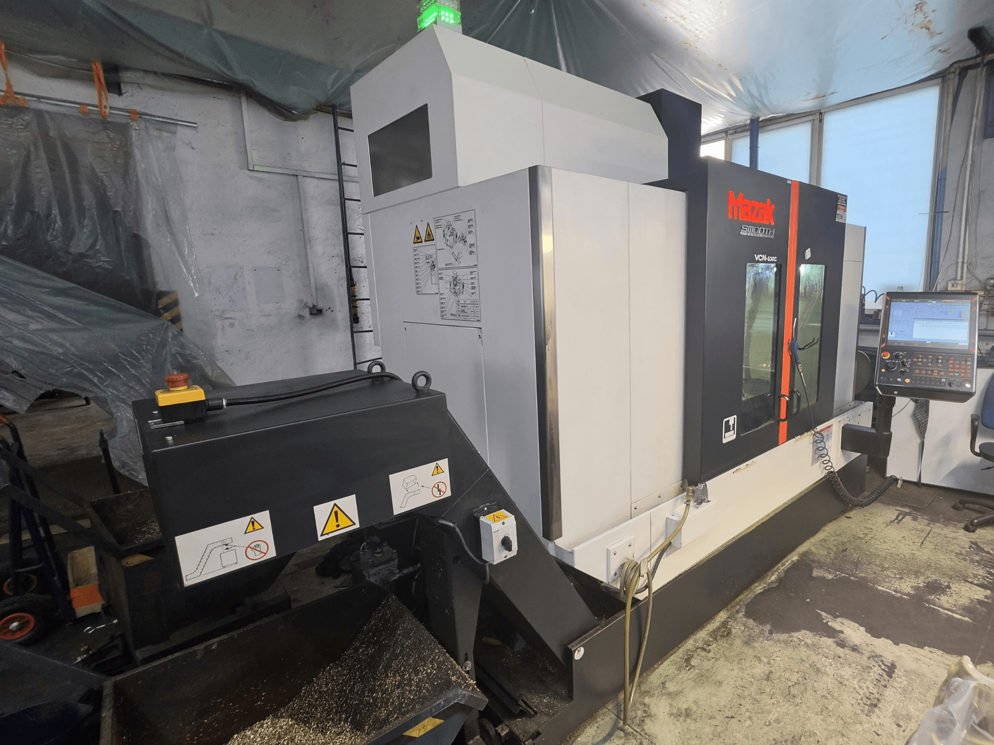 Вертикальний обробний центр Mazak VCN-530C у фронтальному ракурсі: на зображенні видно панель керування, ланцюг інструментів та робочі індикатори.