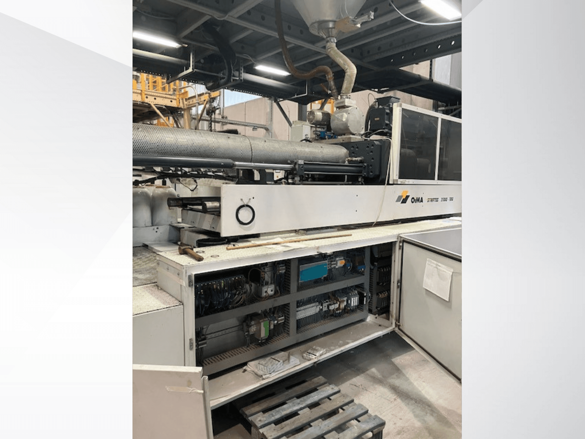 Вид спереду екструдера ОМА 3500 з робочими частинами, панеллю керування та деталями електропроводки. Важка техніка в промислових умовах.