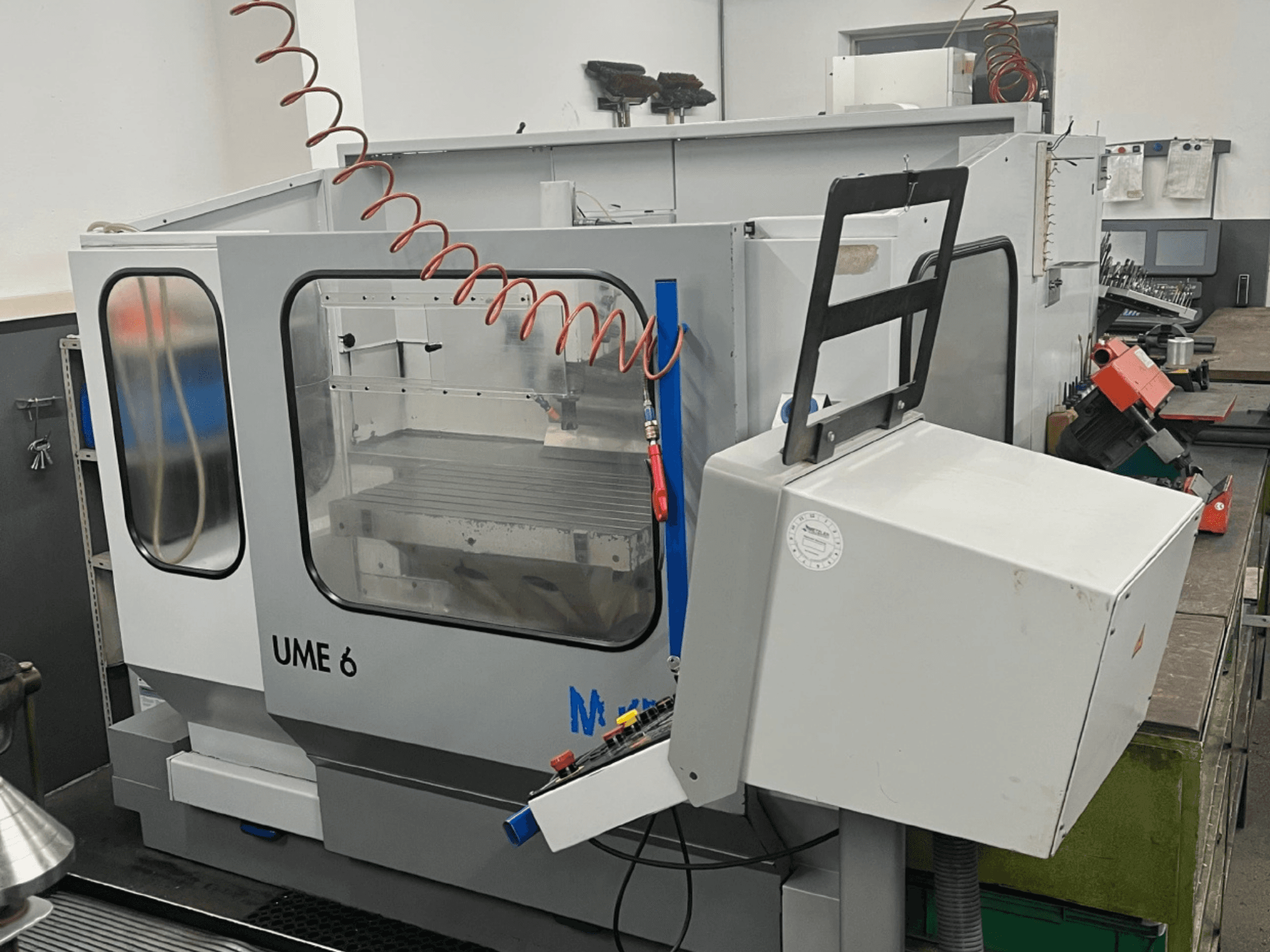Універсальний обробний центр MIKRON UME600 в майстерні, вид збоку з панеллю керування та захисним кожухом.