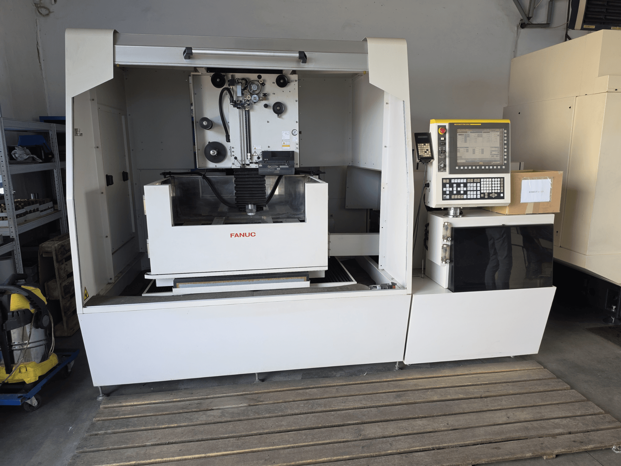 Машина для дротової електроeroзійної обробки FANUC ROBOCUT alpha-1iD: вид спереду, на якому видно панель керування, робочу зону та компактну конструкцію в умовах цеху.