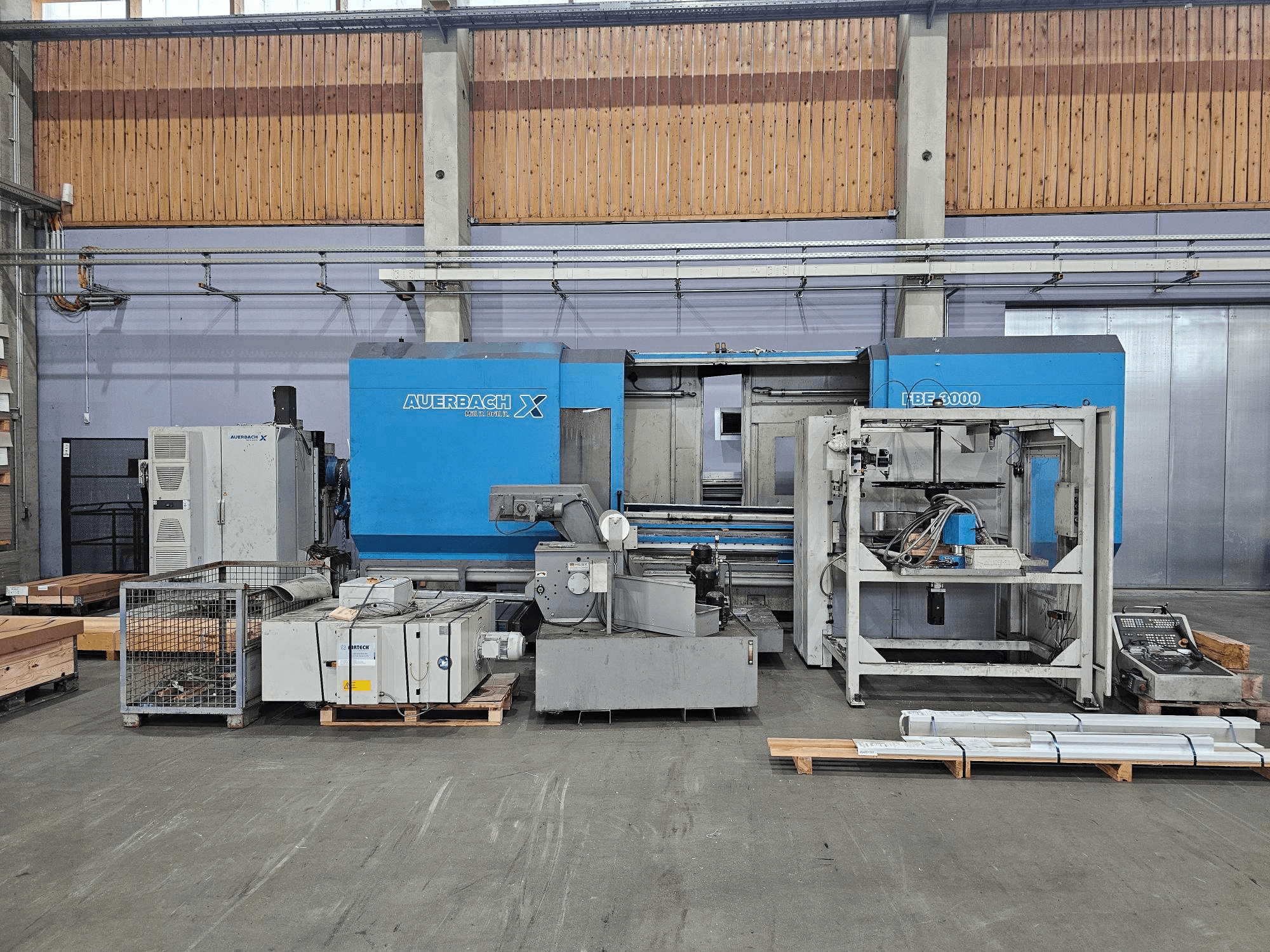 Машина Auerbach X LBF-3000 у заводських умовах, вид збоку, з сірими та синіми компонентами та видимою панеллю керування.