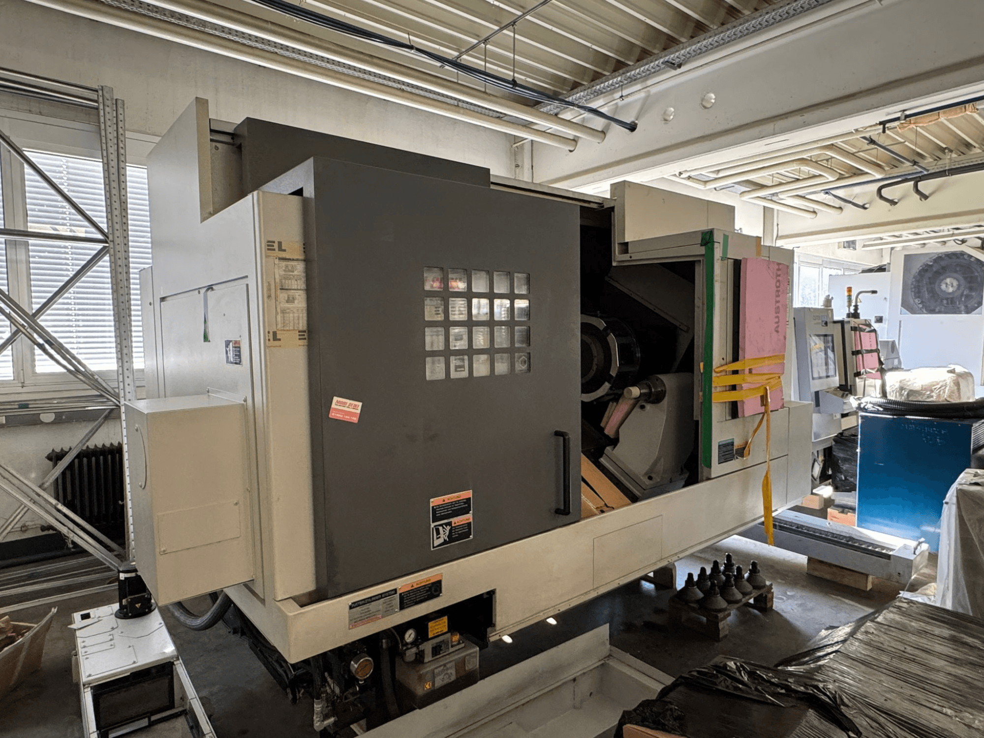 Горизонтальний токарний верстат MORI SEIKI NL 3000 MC/700, вид спереду з панеллю управління, зоною зберігання та захисним чохлом.