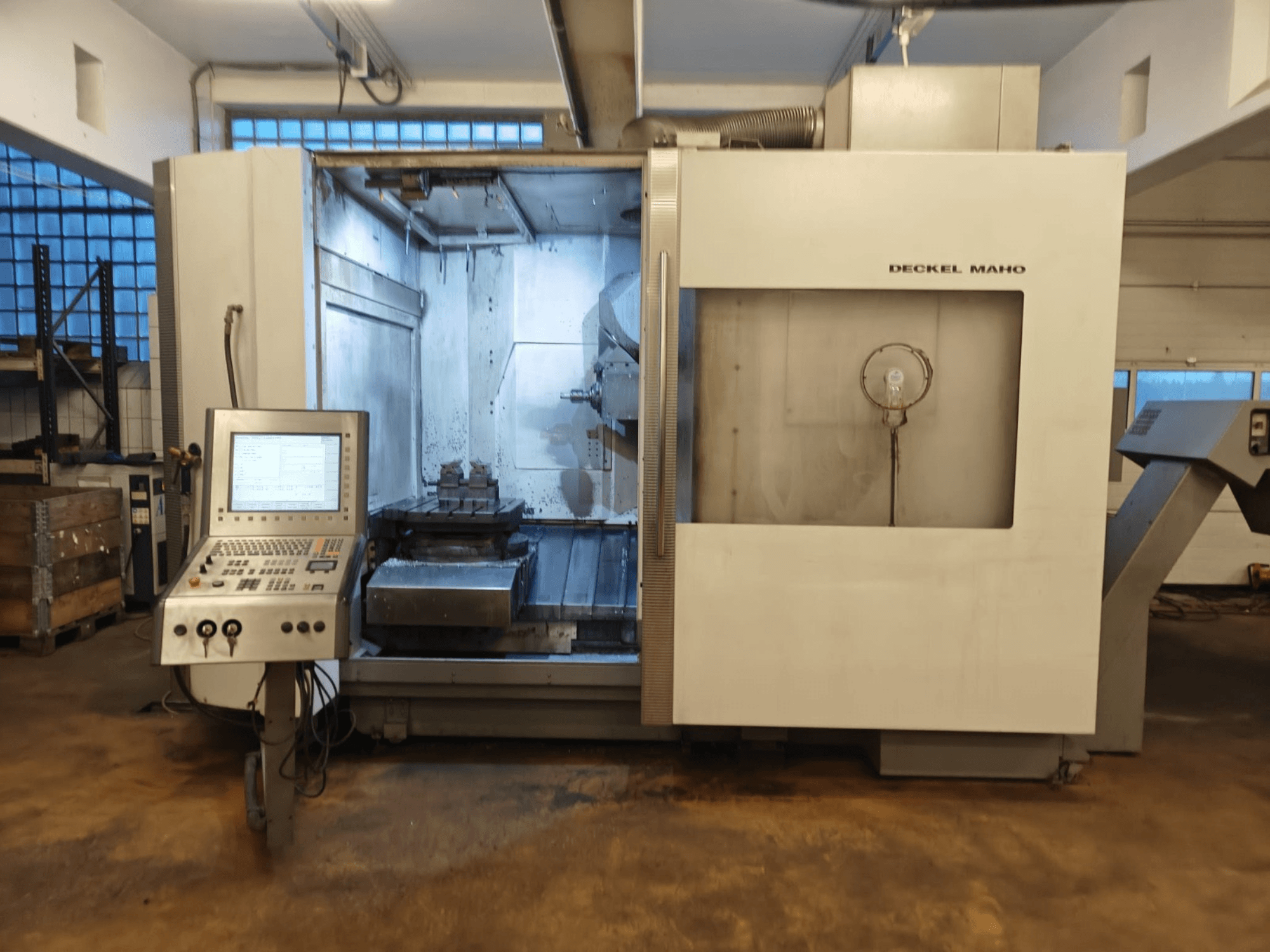 Універсальний обробний центр DECKEL MAHO DMC 60U, вид спереду, з панеллю керування та робочою зоною з установкою заготовки.
