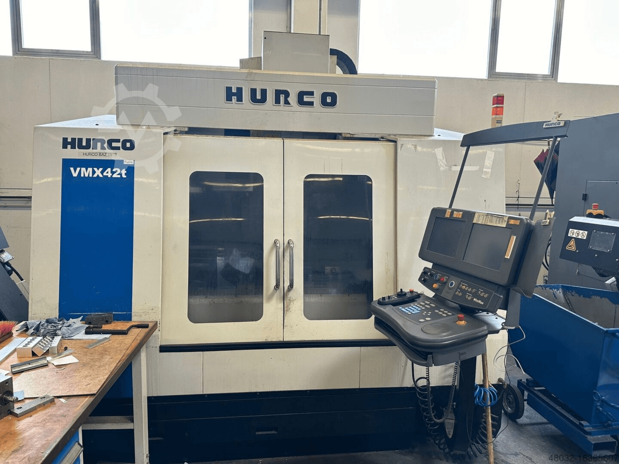 Вертикальний обробний центр Hurco VMX42t, вид спереду, на якому видно панель управління та внутрішню частину верстата з інструментами та заготовками.