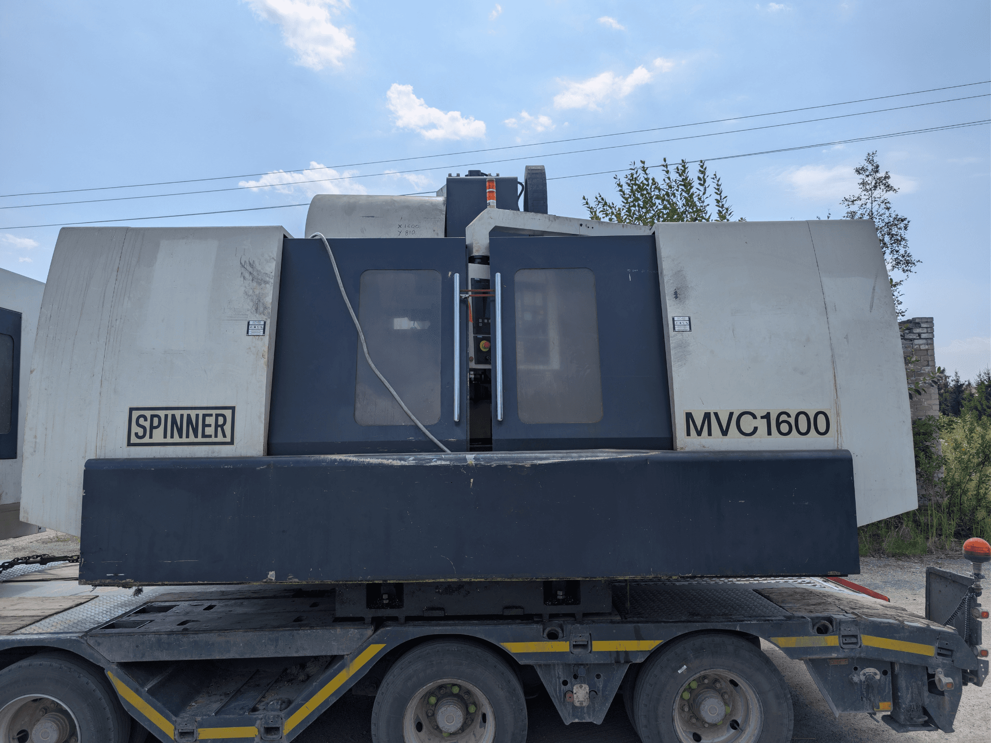 Вертикальний обробний центр SPINNER MVC 1600, вид спереду на вантажівці, на якому видно логотип та велику зону обробки.