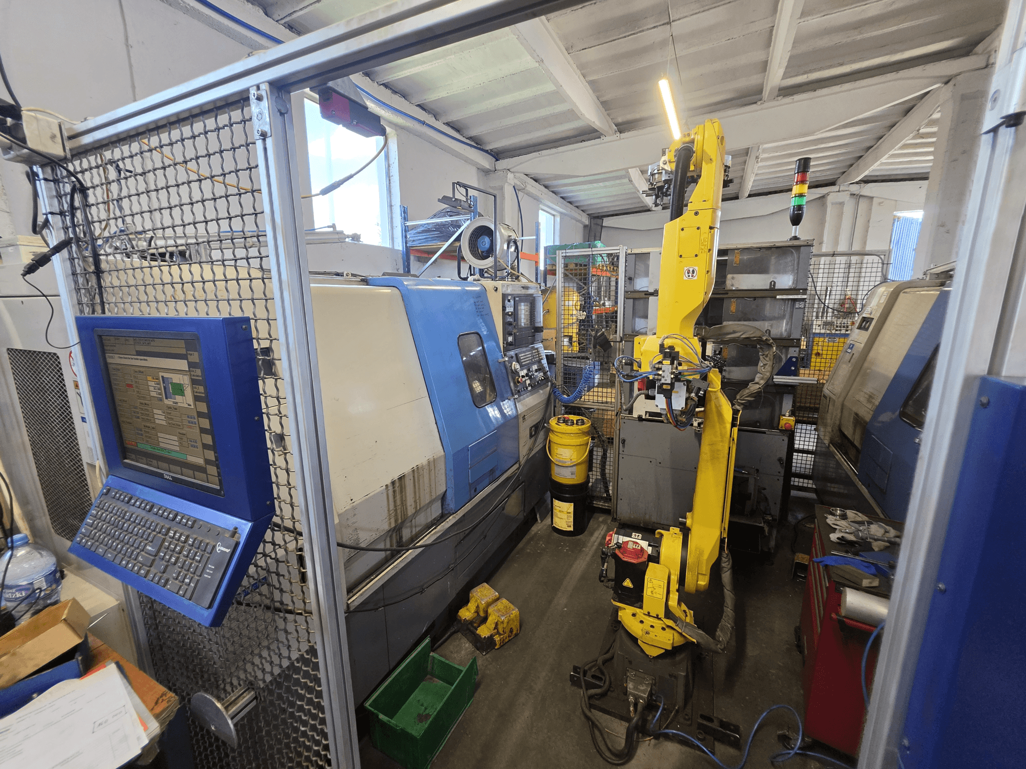 Горизонтальний токарний верстат Hyundai HIT-200C з роботом FANUC M-20iA, вид спереду, на якому видно інтерфейс управління та конфігурацію обладнання.