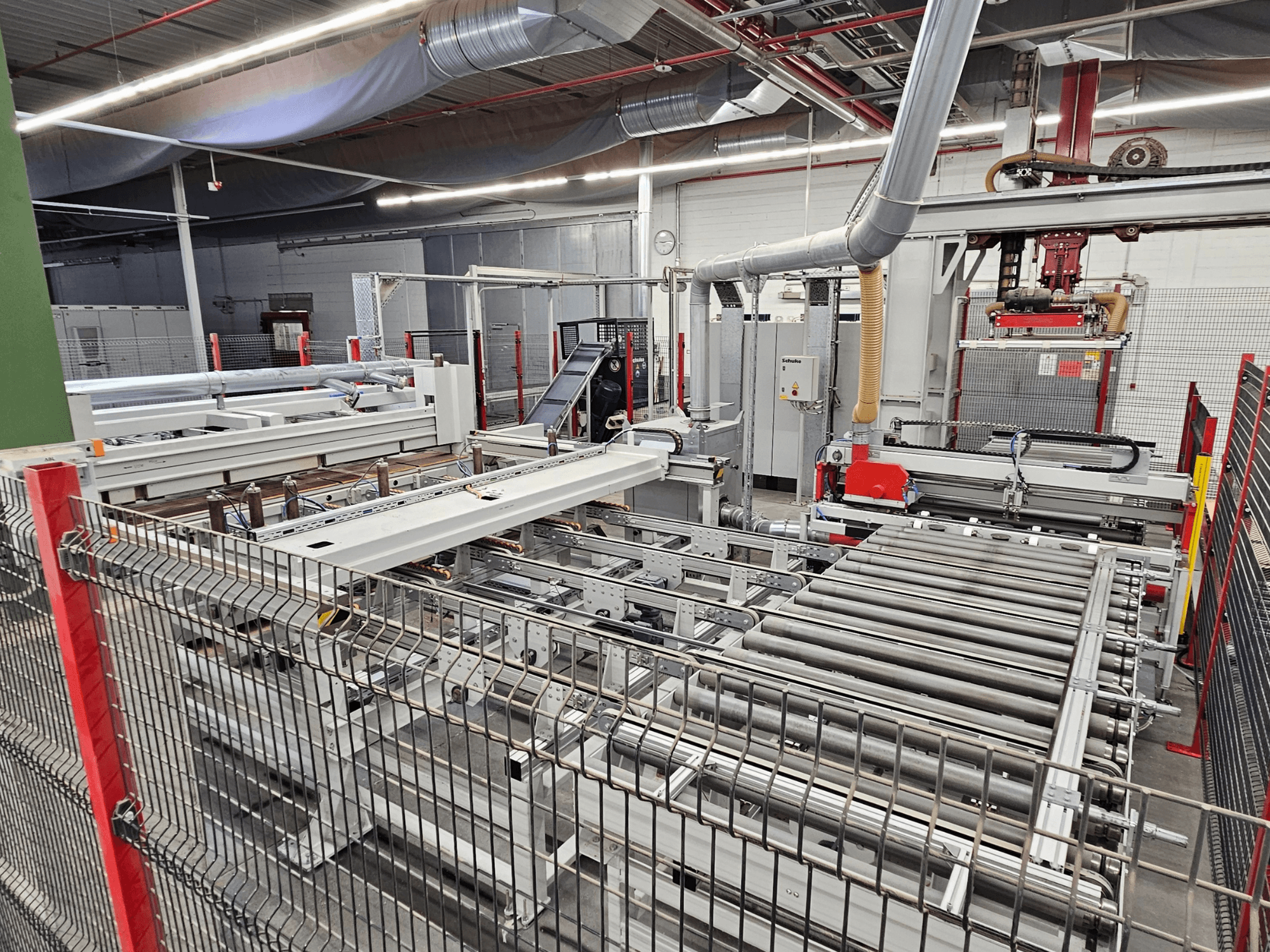 Панельна пила HOLZMA HPP81-3200 показана спереду, з роликами конвеєра та компонентами машини в умовах цеху.