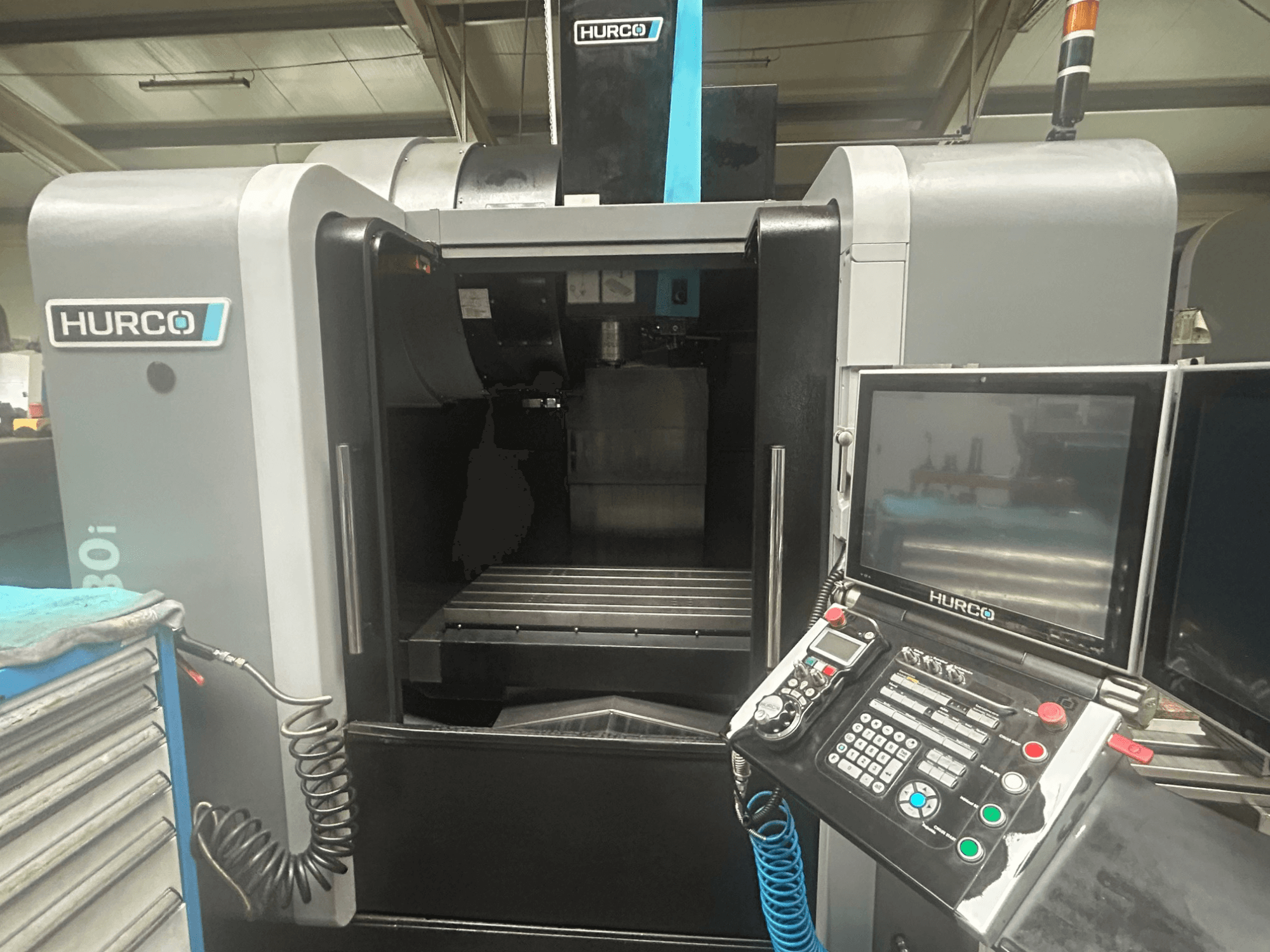 Вид спереду верстата з ЧПК Hurco VM30i з панеллю керування з кнопками, дисплеєм і місцем для зберігання інструменту.