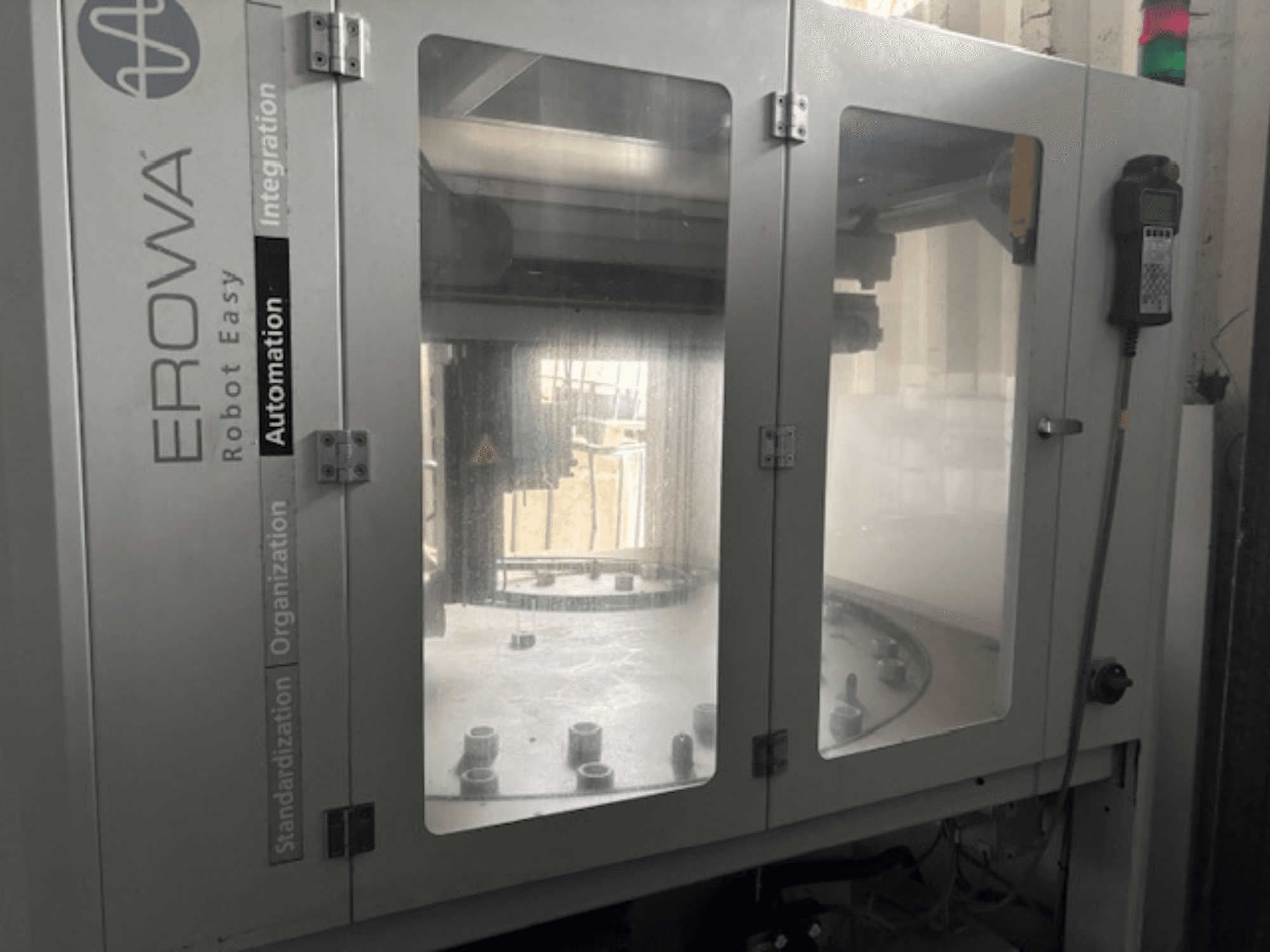 Вид спереду EROWA Robot Easy Automation; прозорі двері, видимі компоненти автоматизації та панель керування.