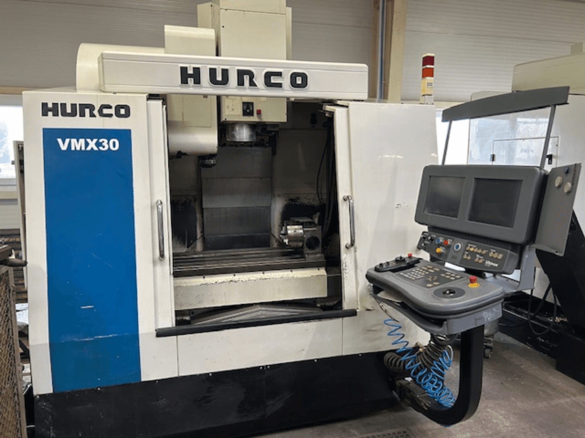Фрезерний верстат з ЧПК Hurco VMX30 в майстерні, вид спереду; оснащений панеллю керування з двома екранами та кнопками керування.