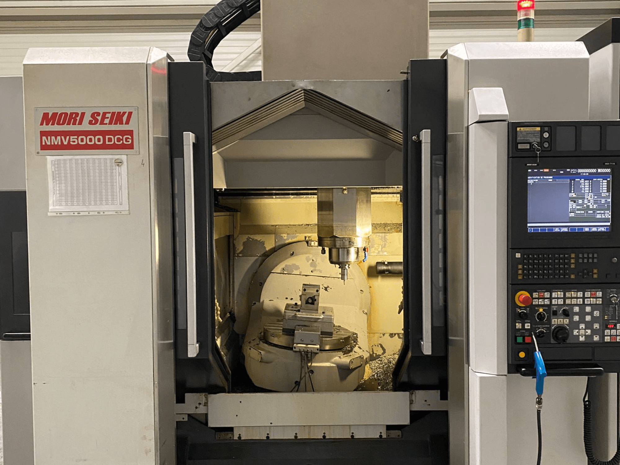 Універсальний обробний центр MORI SEIKI NMV 5000DCG, вид спереду з панеллю керування та внутрішньою зоною обробки.