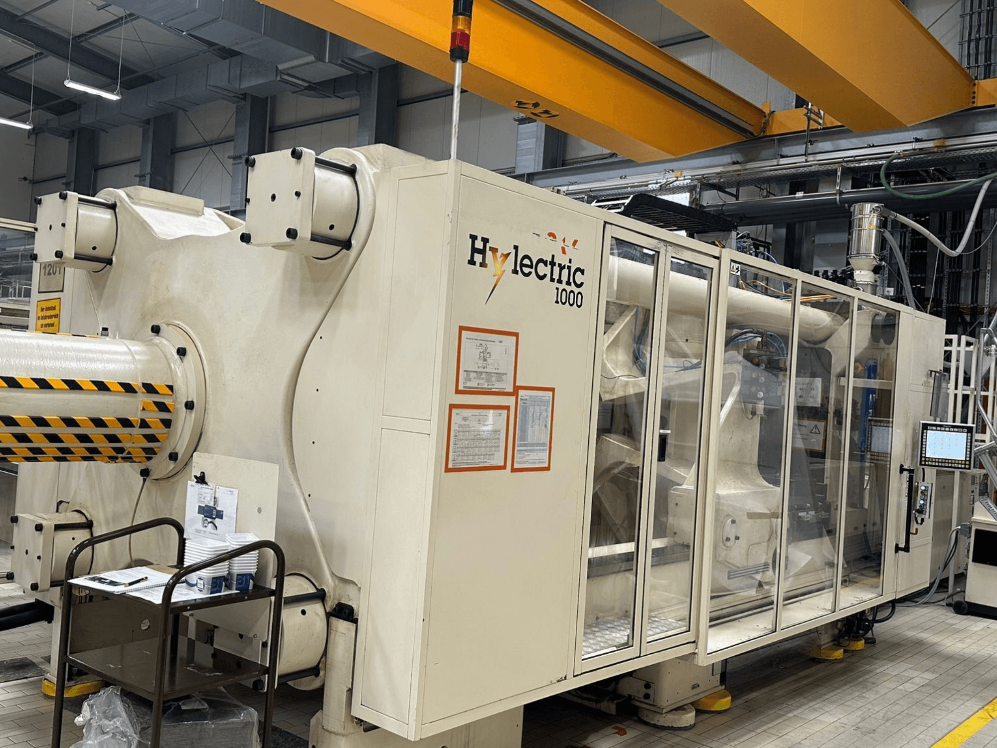 Електрична термопластавтомат Husky Hylelectric H1000 RS95/80, вид збоку, на якому видно панель керування та засоби безпеки.