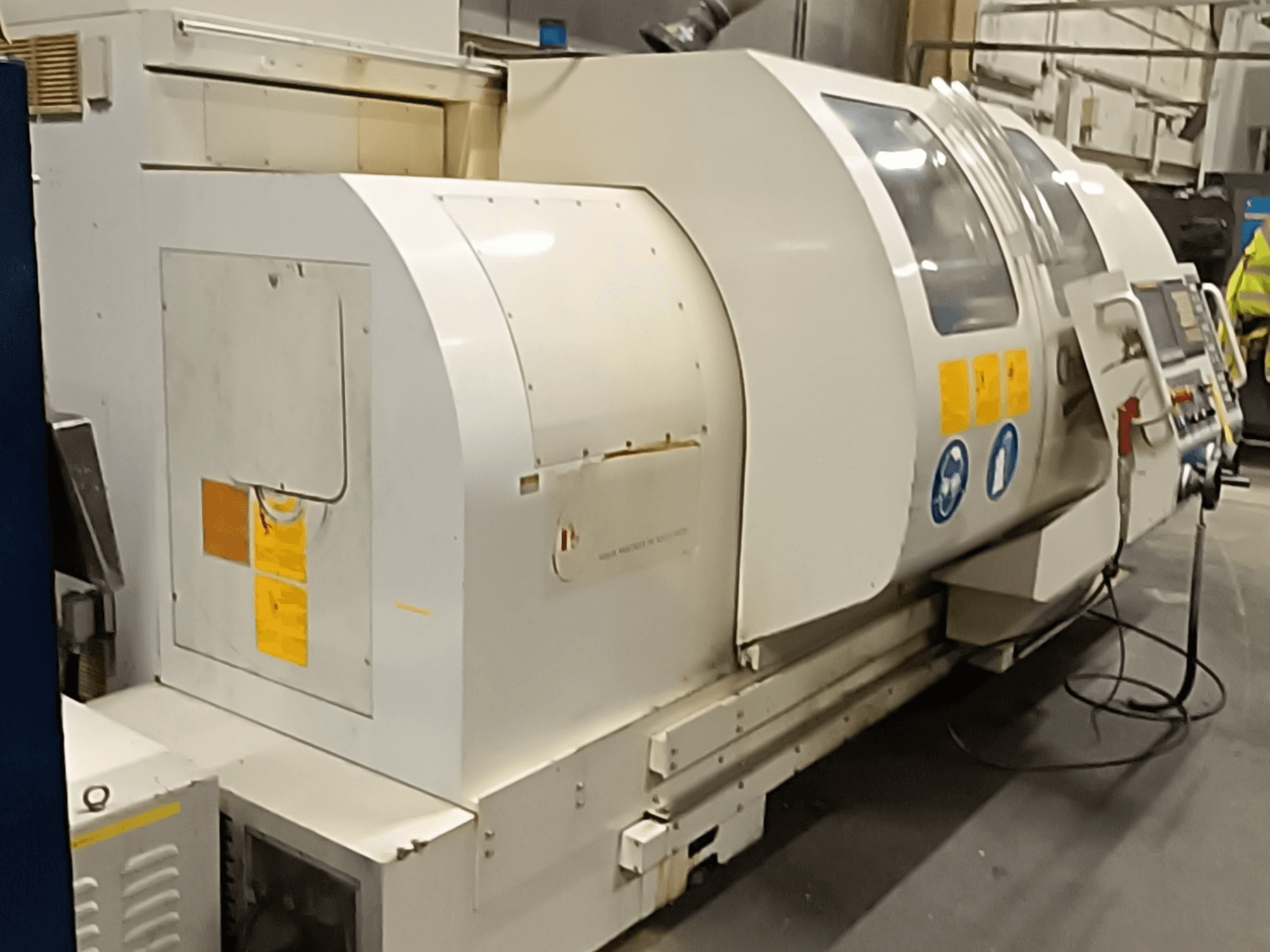 Горизонтальний токарний верстат MONDIALE BNC-2260XL, вид збоку, з панеллю керування та етикетками безпеки.