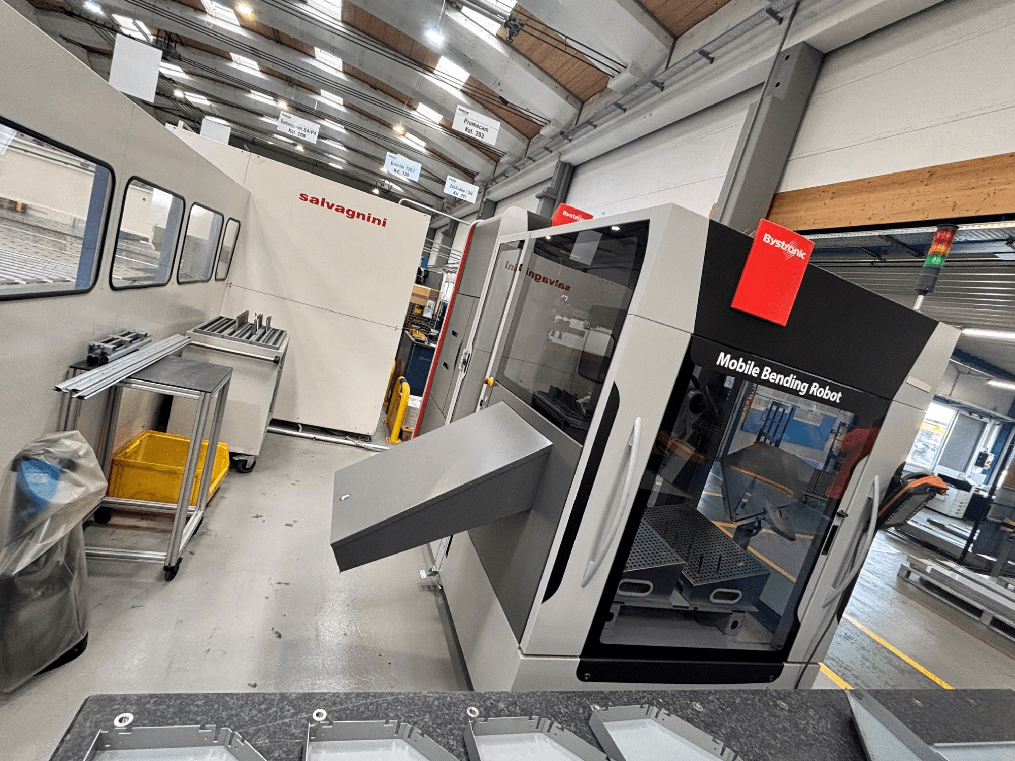 Гнучкий прес Bystronic Xpert 40/1030, вид спереду, на якому видно мобільний робот для гнуття та робочу зону зі металевими деталями на столі.
