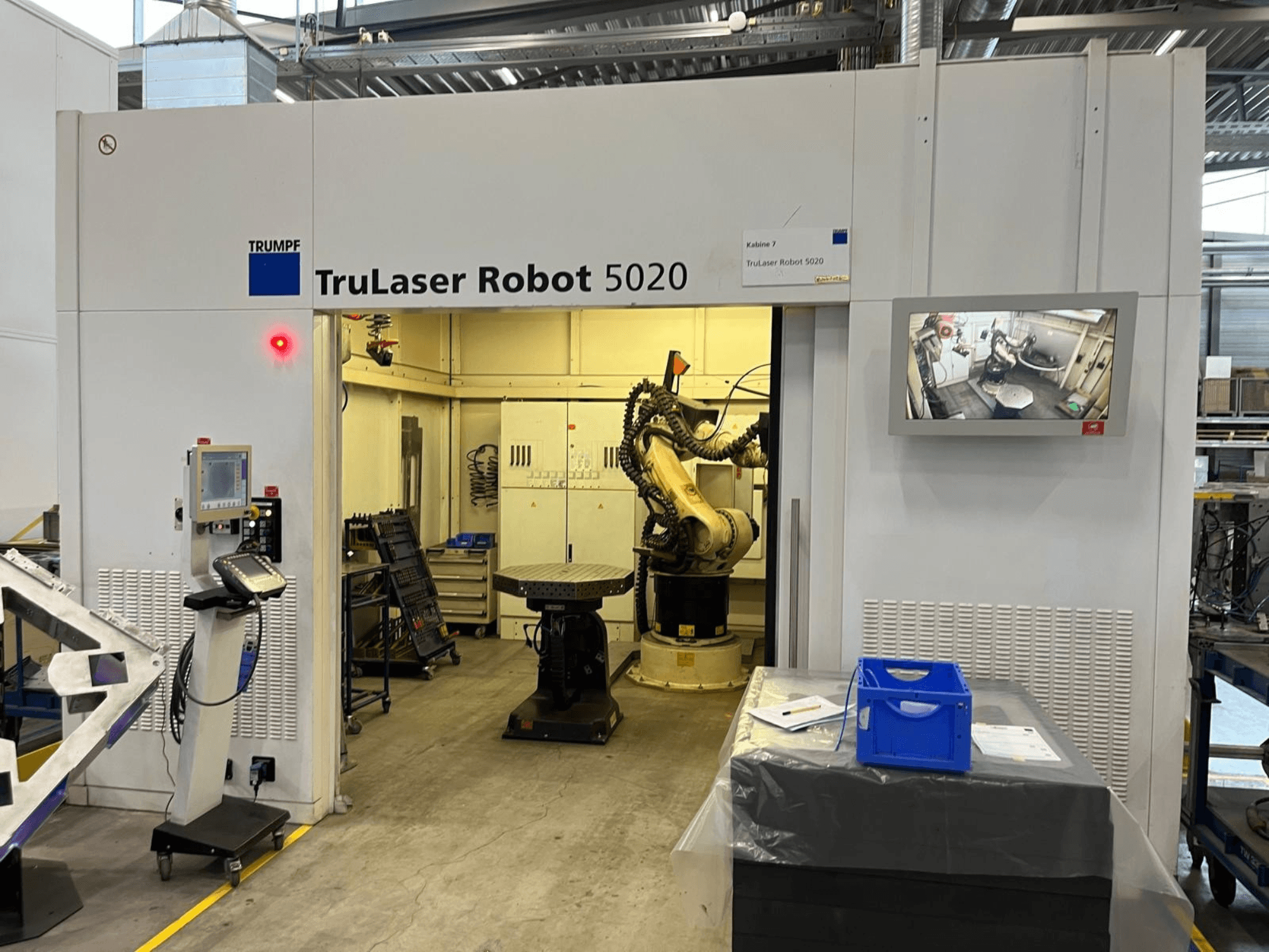 TRUMPF TruLaser Robot 5020 у промисловому середовищі: на фото зображено пульт управління, робочий маніпулятор та монітор, на якому відображаються робочі процеси.