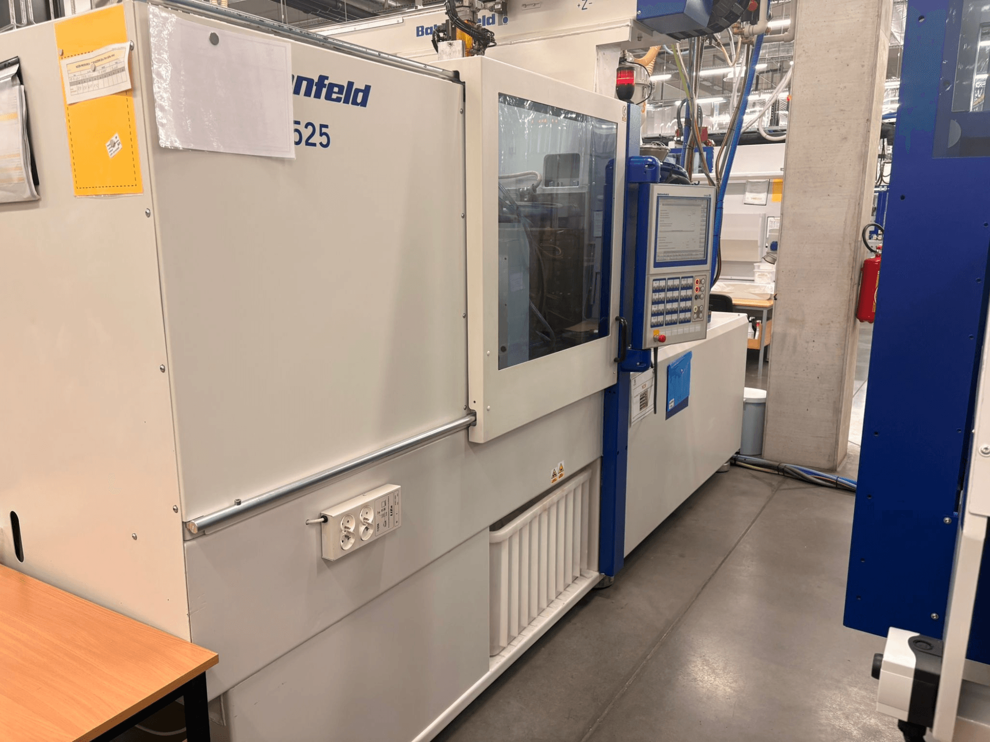 Машини Arburg, модель 620S, вид спереду, де показано панель керування та порти живлення у заводському виконанні.