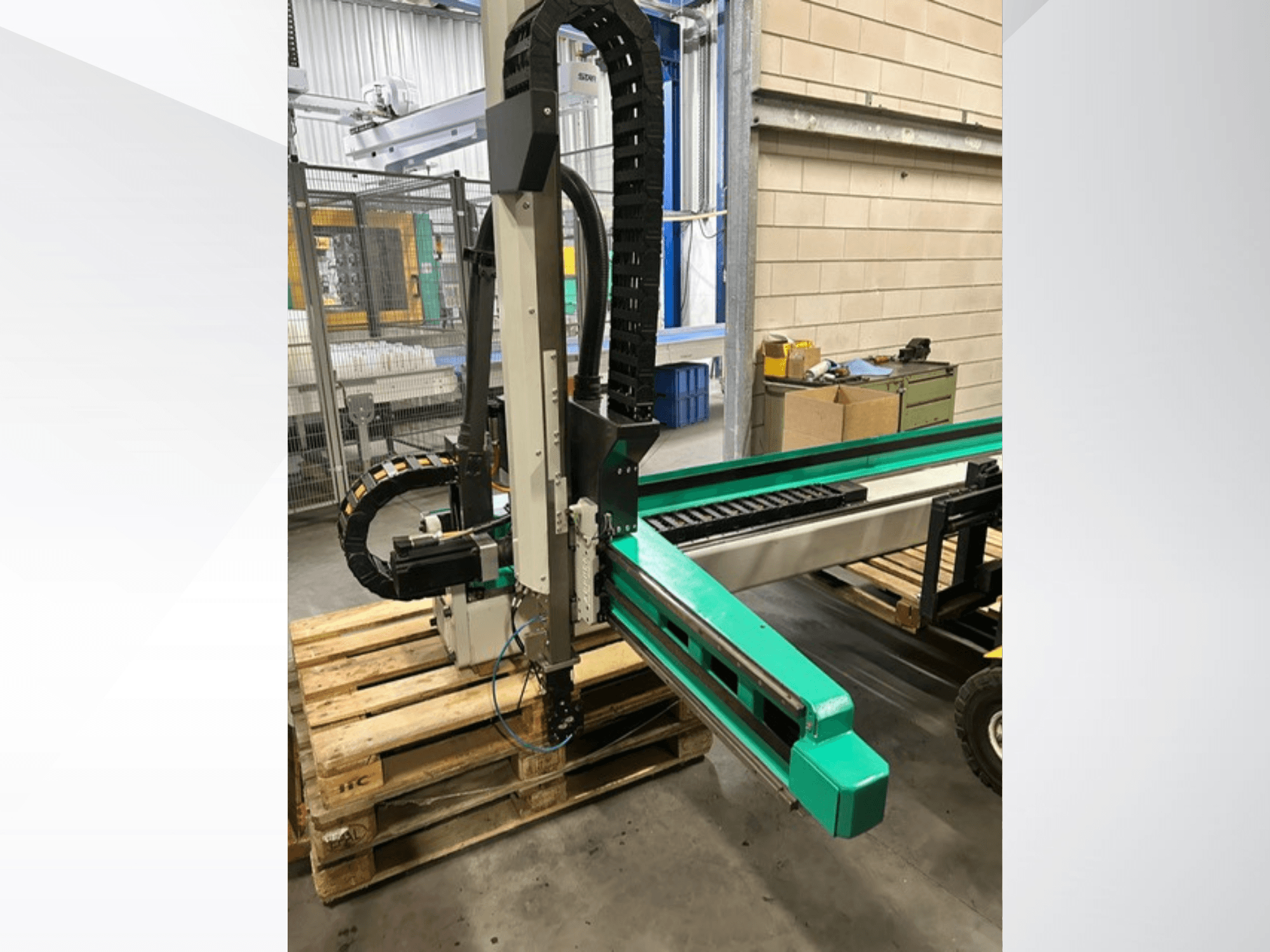 Arburg Multilift Select 15 кг, вид збоку на систему переміщення заготовок на дерев'яних піддонах, показано роботизований маніпулятор і компоненти керування.