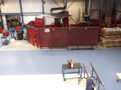 Промисловий робочий простір з червоними зварювальними шторами, машинами та палетами; вид зверху, що демонструє макет та обладнання.