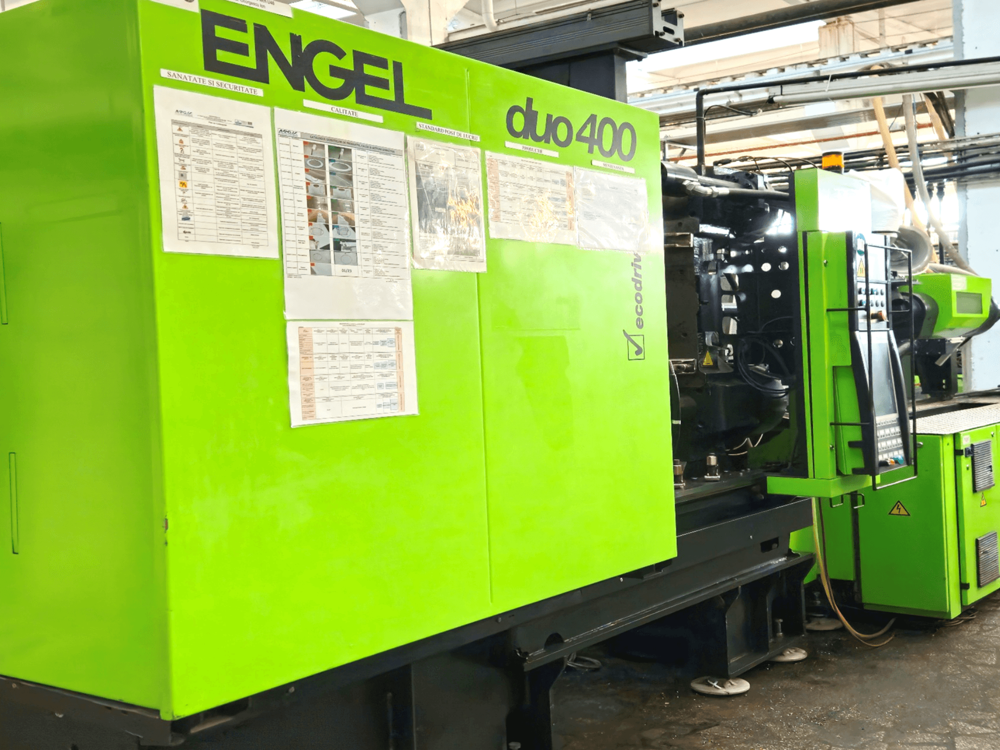 Зелена термопластавтомат ENGEL duo 400, вид спереду, на зовнішній стороні демонструється панель керування та документація з техніки безпеки.