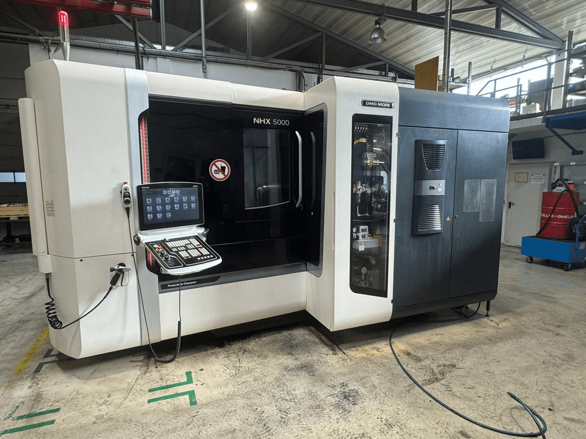 Горизонтальний обробний центр DMG MORI NHX 5000, вид спереду з видимою панеллю керування та індикаторами безпеки.