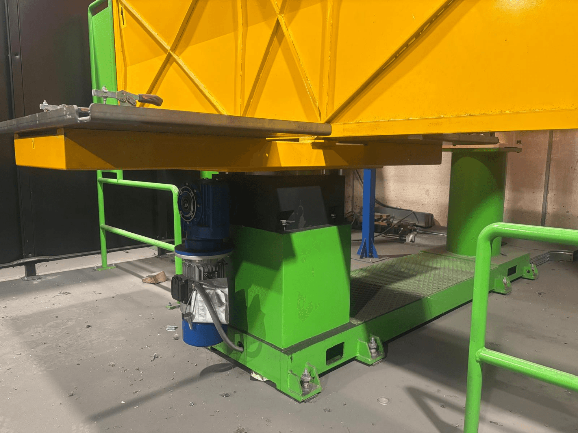 Зелено-жовта промислова техніка з низьким видом спереду, з двигуном і платформою з текстурованою поверхнею.