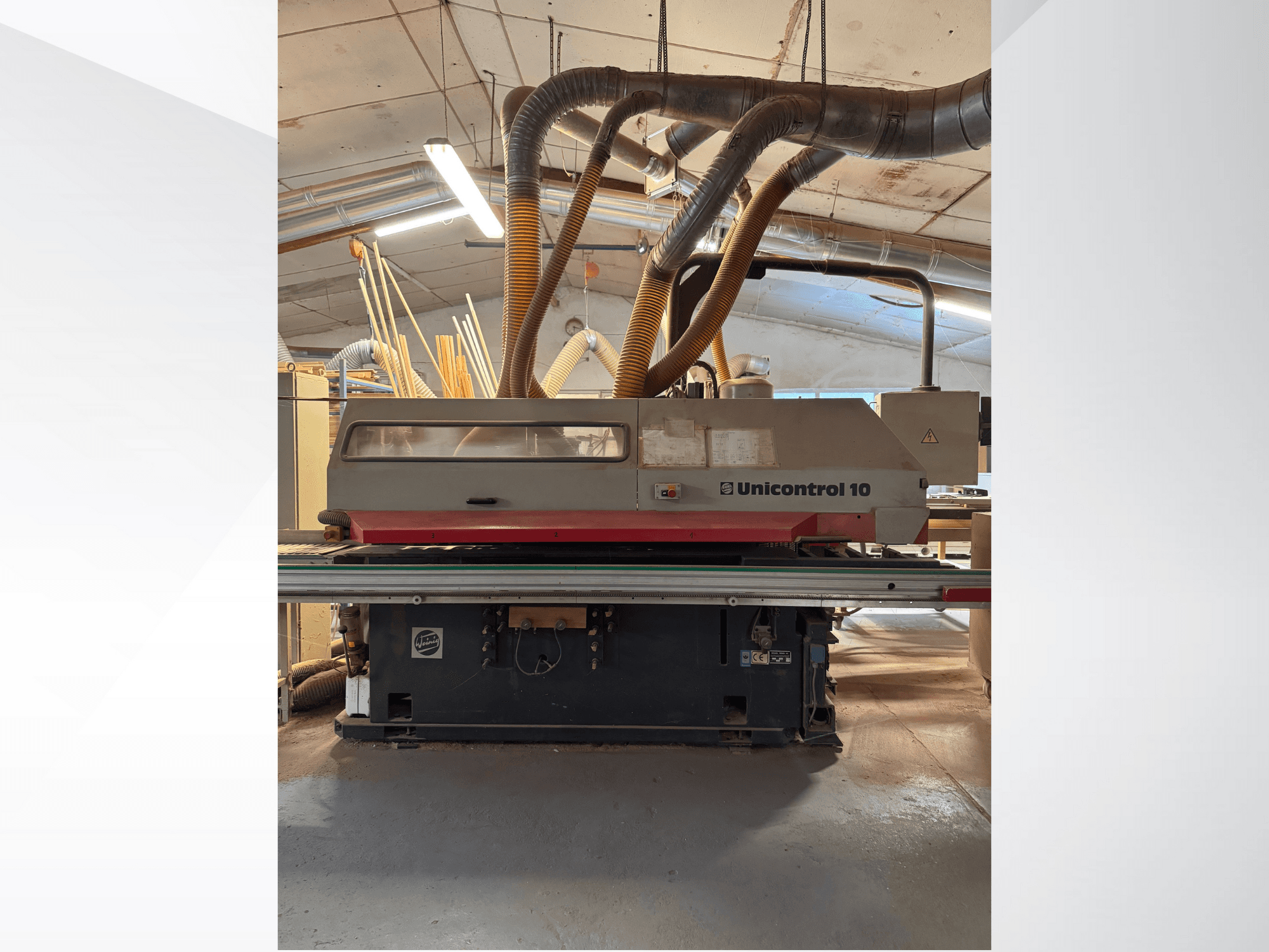 Вид спереду деревообробного верстата Unicontrol 10 з трубками для відсмоктування пилу та органами керування.