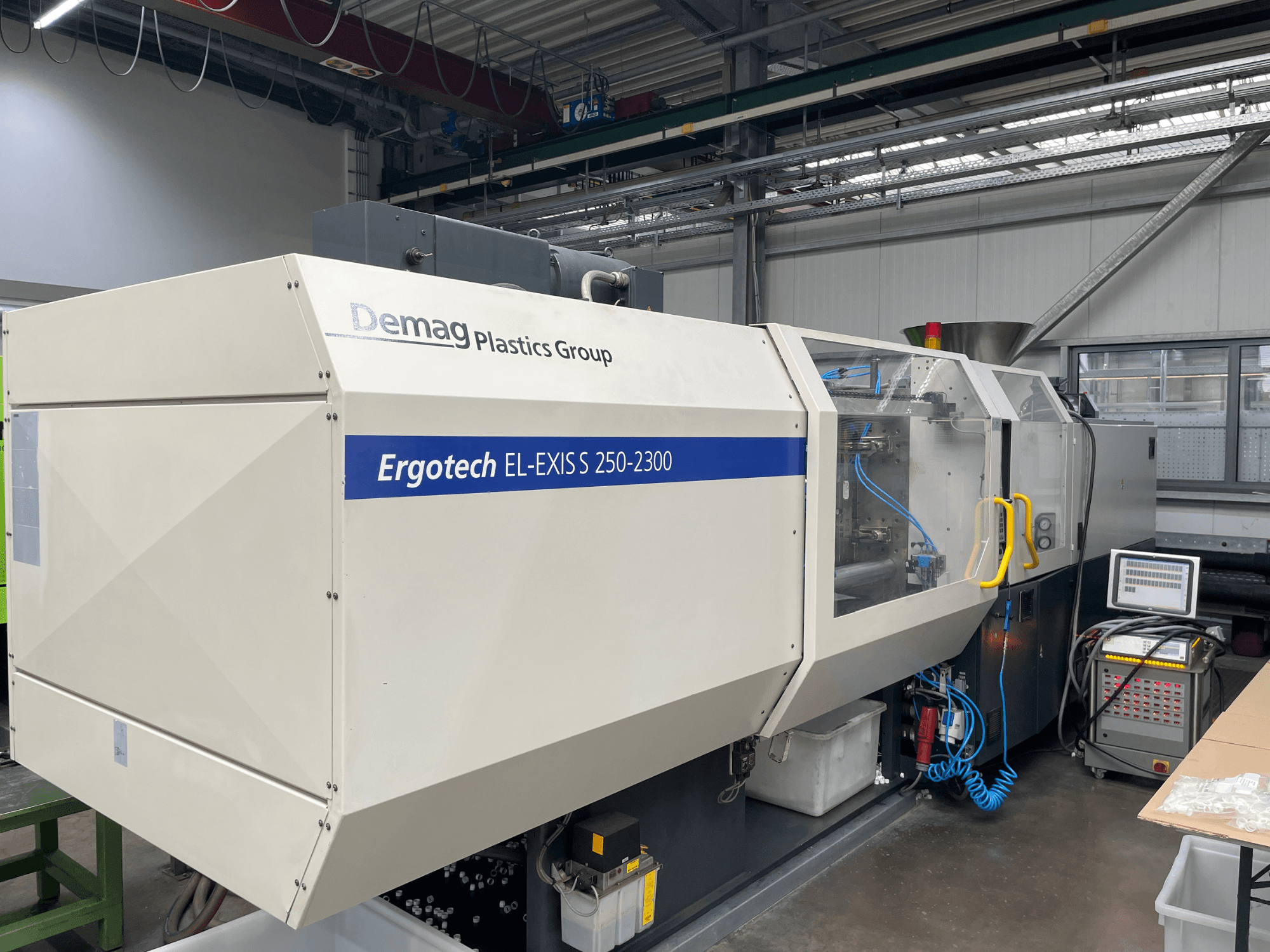 Термопластавтомат Demag Ergotech EL-EXIS S 250-2300, вид збоку, демонстрація панелі керування та системи подачі.