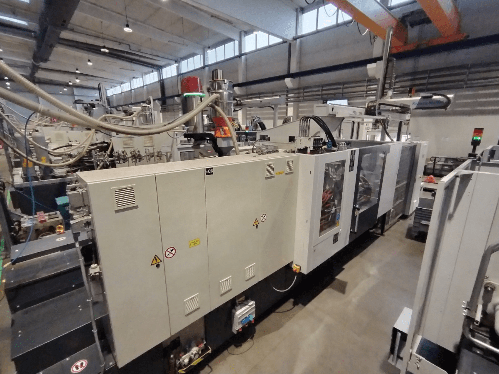 Промислова машина для лиття під тиском показана збоку, з панеллю керування та попередженнями про безпеку. Марка: Невідомо.