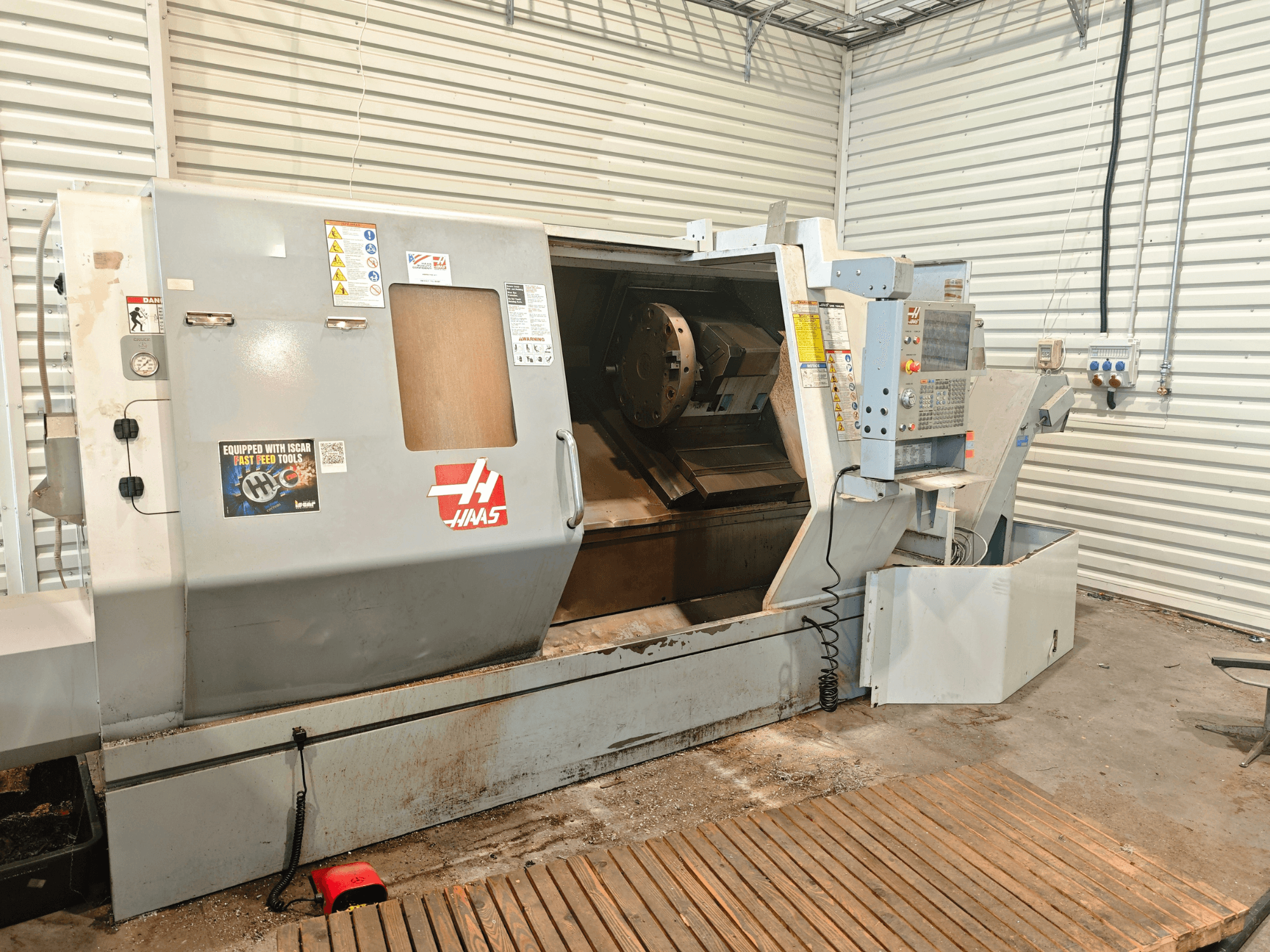 Горизонтальний токарний верстат Haas SL-40HE, вид спереду, на якому видно панель управління, робочу зону та попереджувальні наклейки.