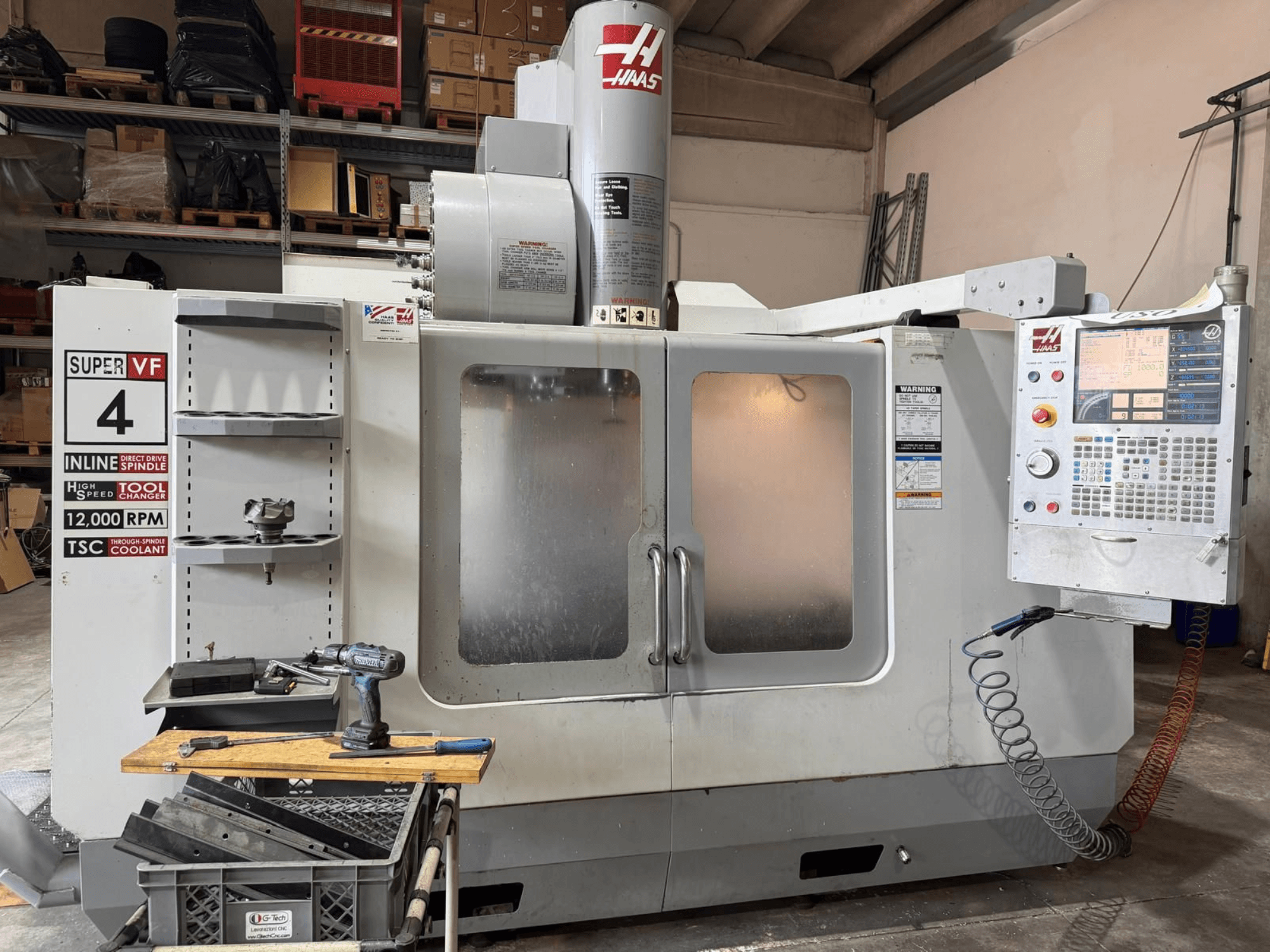 Вигляд спереду вертикального обробного центру HAAS VF-4SSHE з пультом управління, інструментальною полицею та шпинделем, що обертається зі швидкістю 12 000 об/хв; високошвидкісний прецизійний верстат.