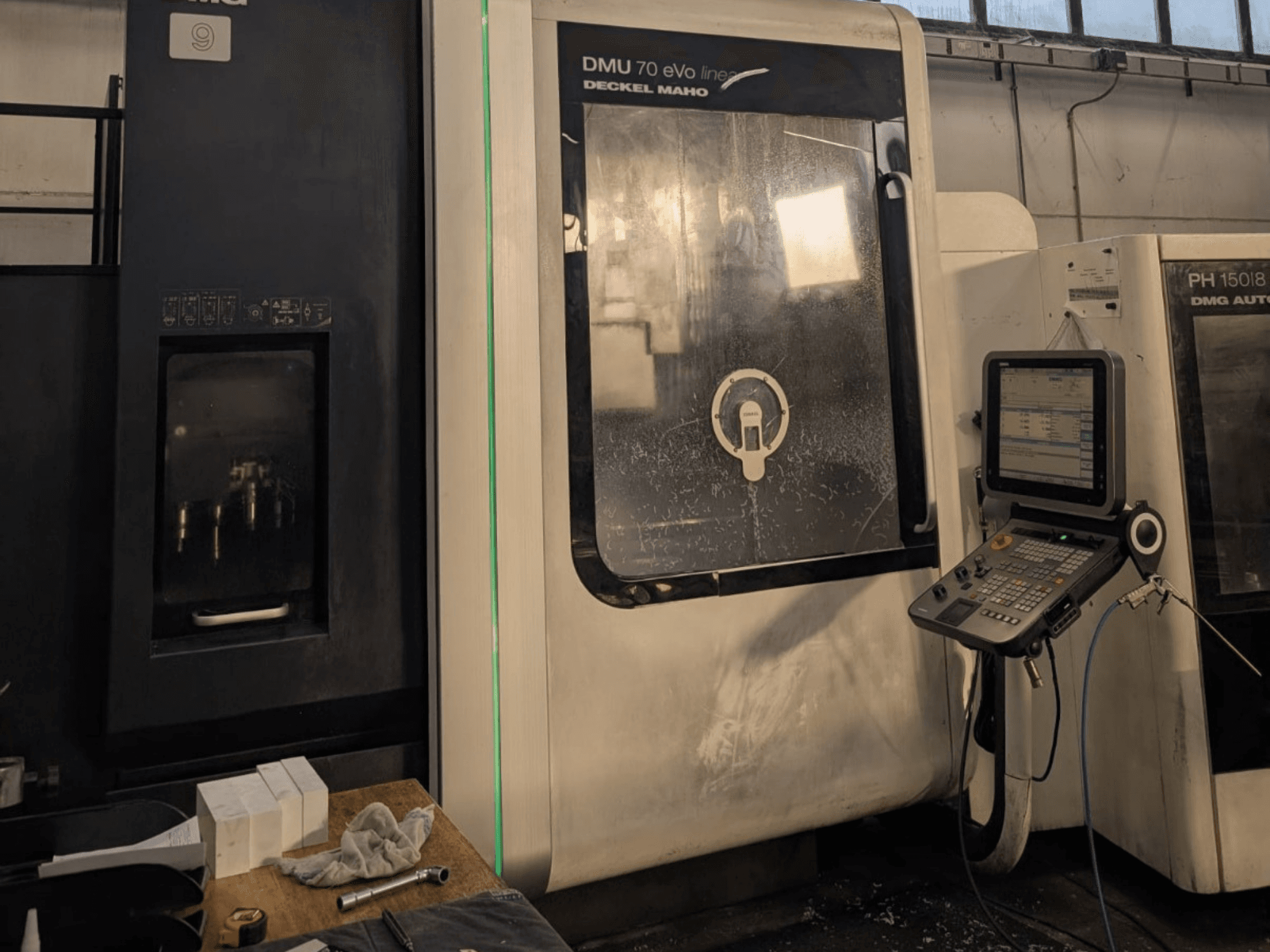 DMG DECKEL MAHO DMU 70 EVO Лінійний вертикальний обробний центр, вид спереду з панеллю керування, інструментами та робочою зоною.