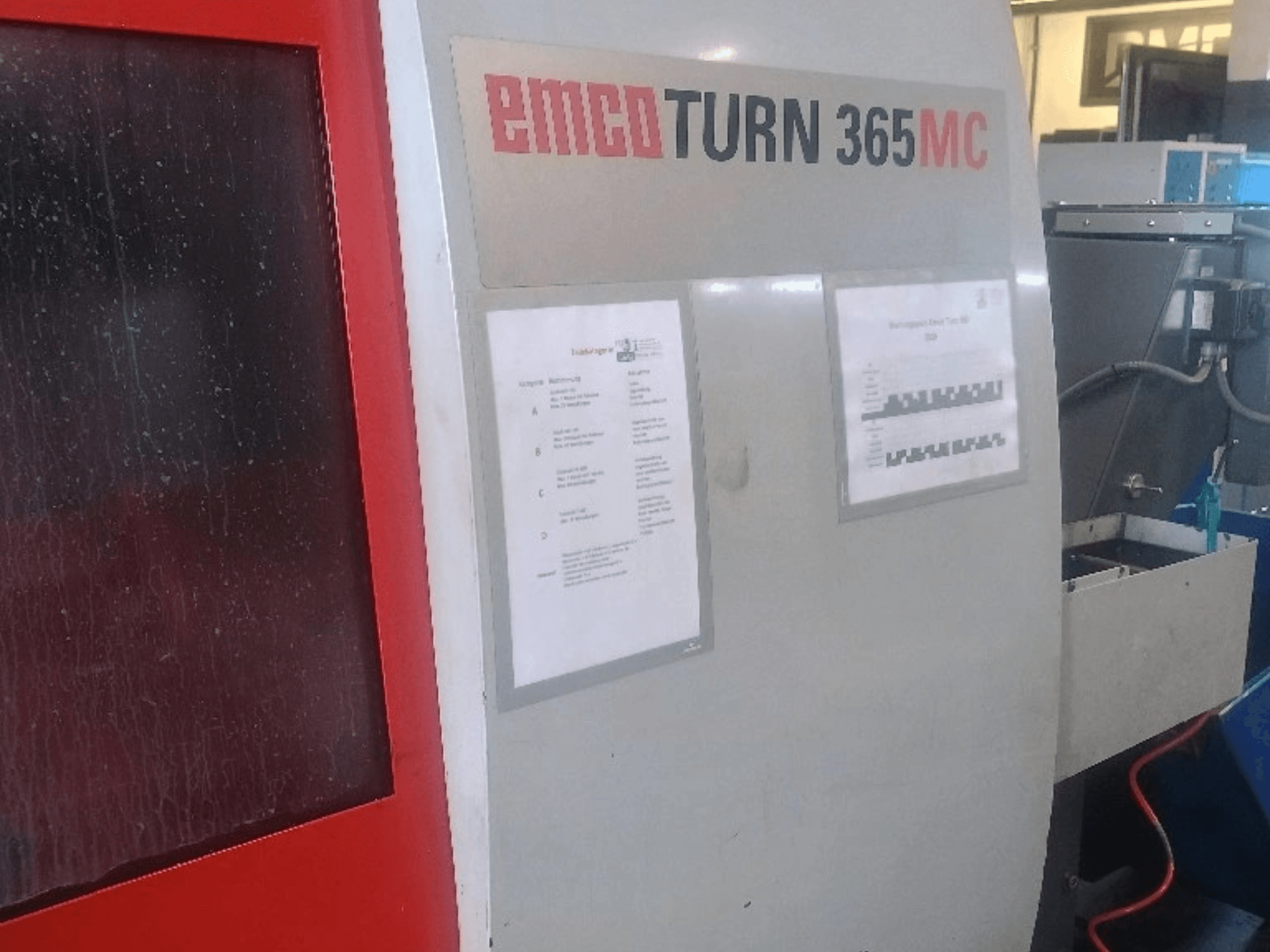 Горизонтальний токарний верстат EMCO EmcoTurn 365 MC, вид збоку: видно панель управління, інструкції та синій бак для охолоджувальної рідини.