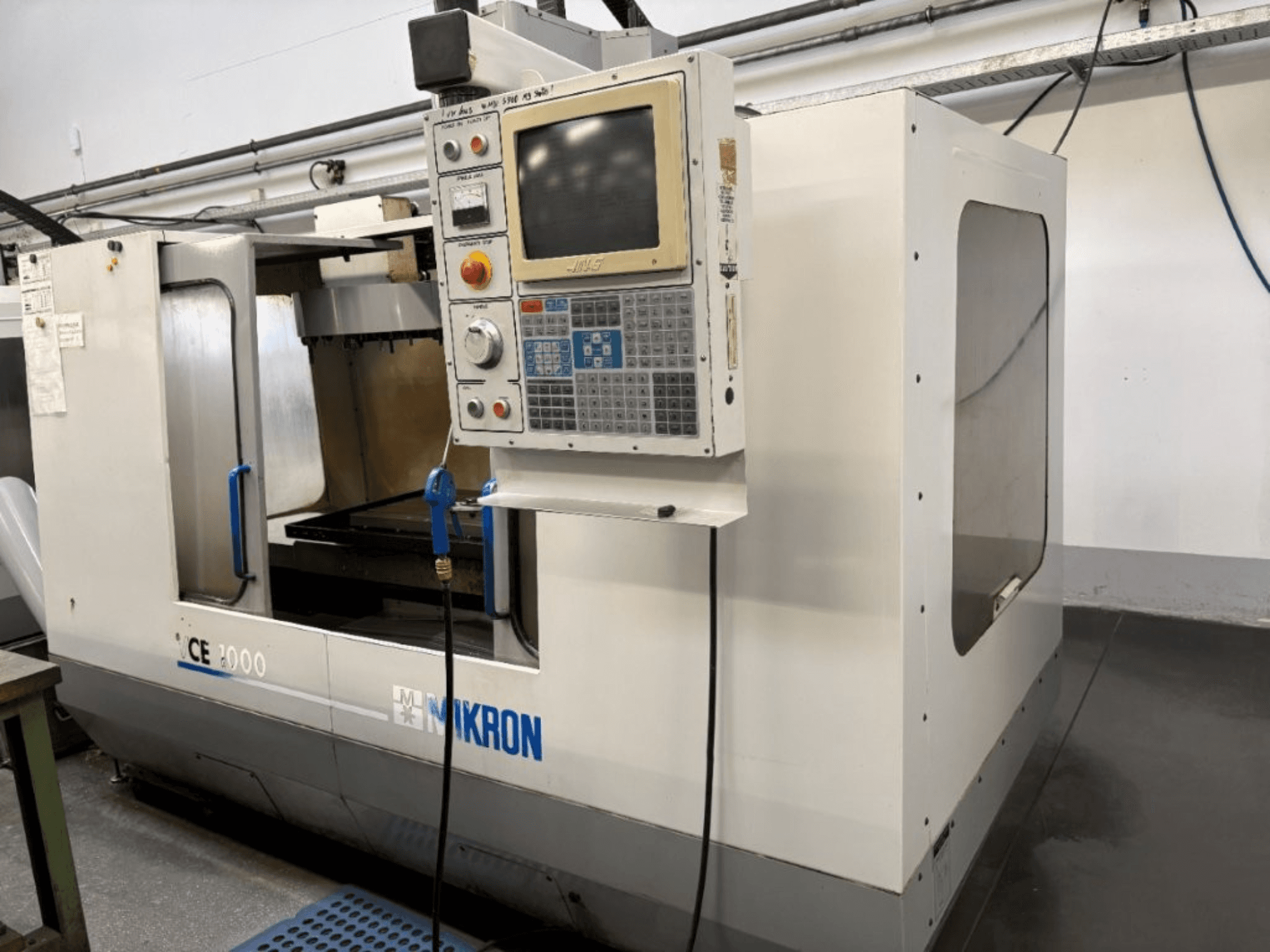Верстат з ЧПК Mikron CE 2000, вид спереду; має панель керування з кнопками та екраном, сріблястий зовнішній вигляд та робочу зону.
