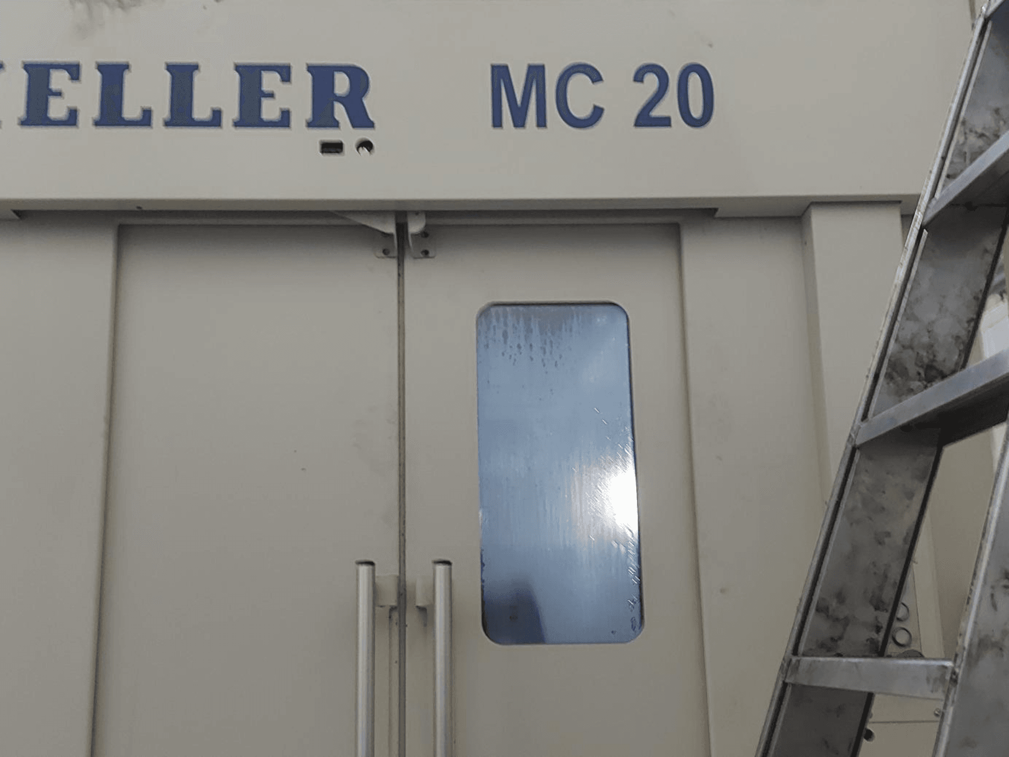 Вид спереду горизонтального обробного центру HELLER MC 20 з дверними ручками і невеликим вікном. Сходи збоку.